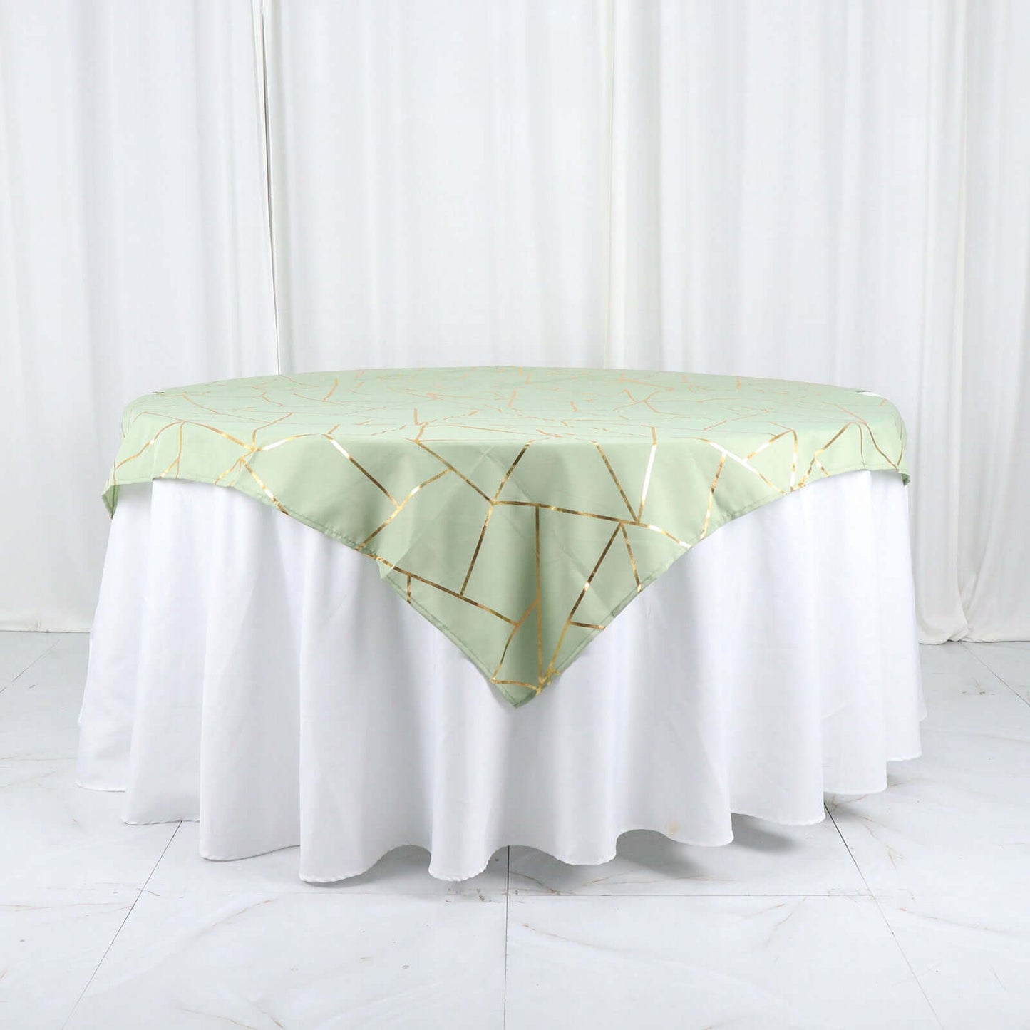 Sage green square overlay with gold foil geometric pattern on a table.