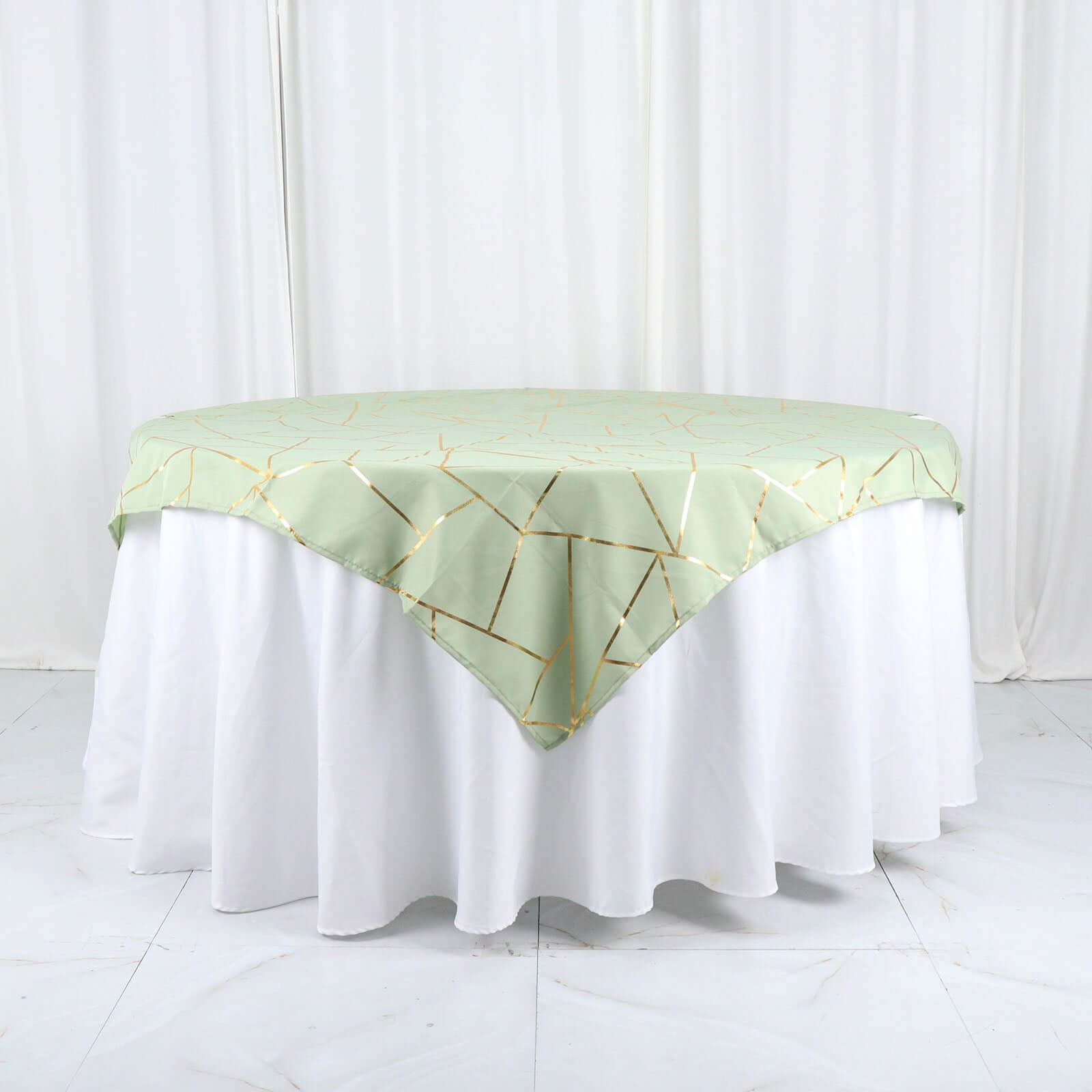 Sage green square overlay with gold foil geometric pattern on a table.
