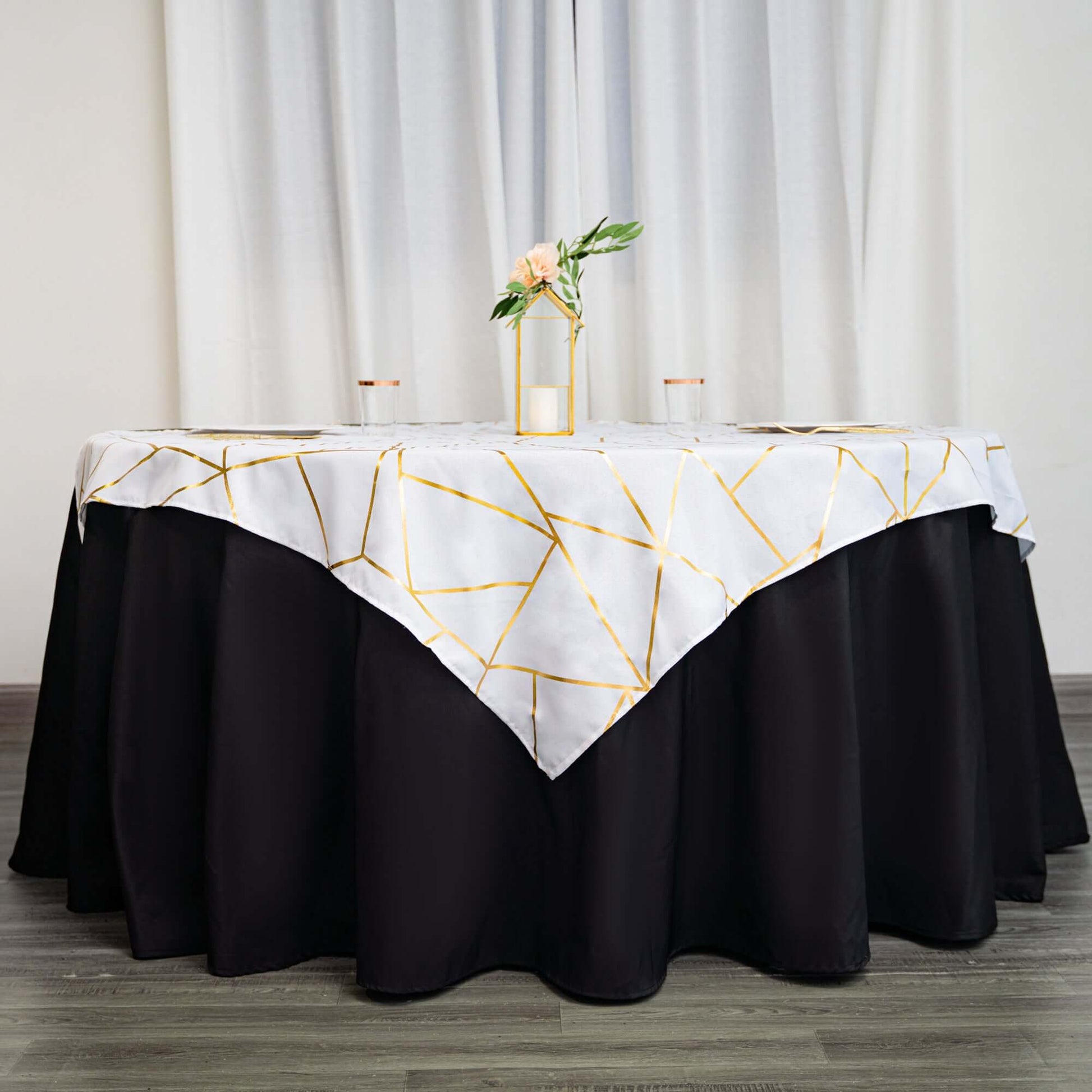 White square overlay with gold foil geometric pattern on a black table.