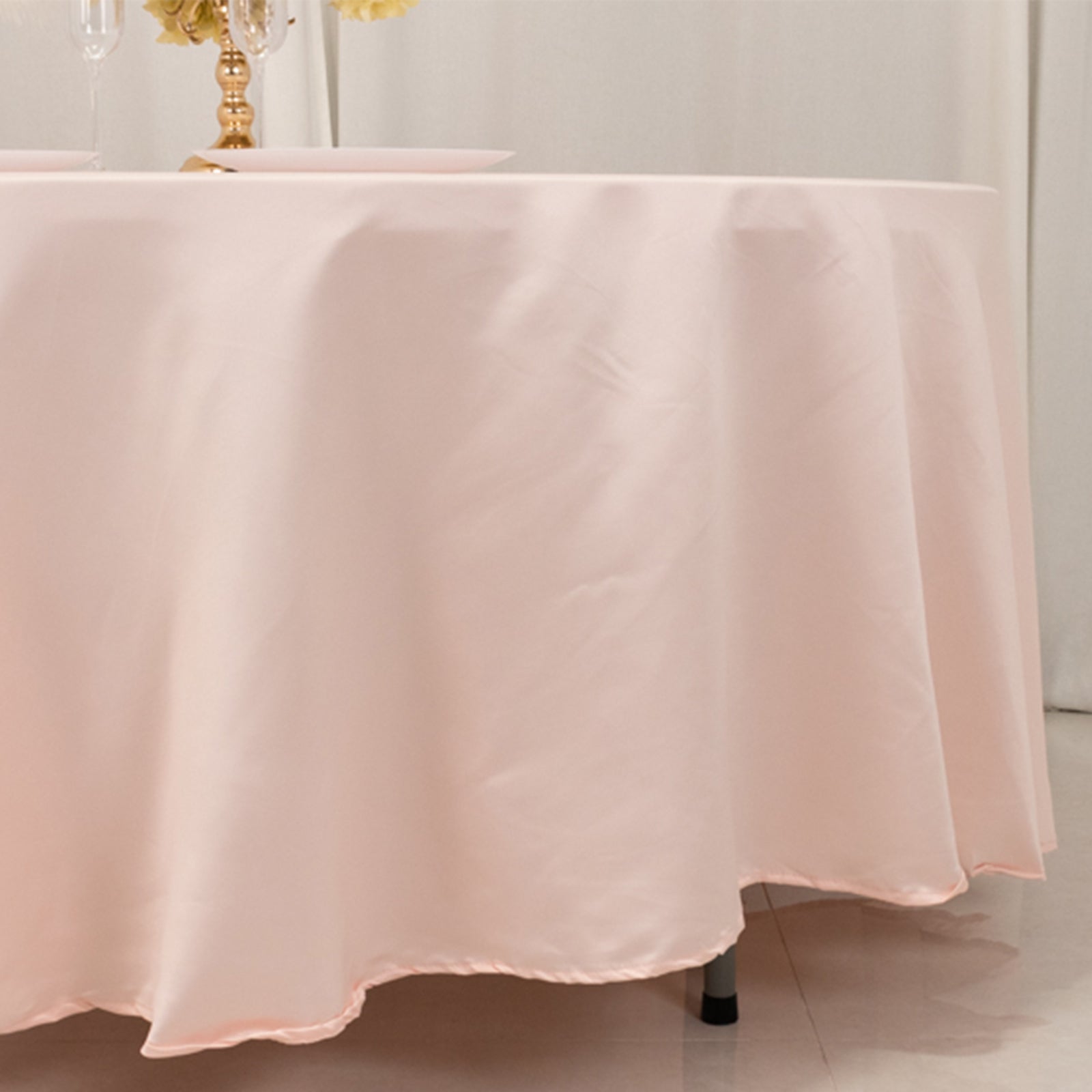 Blush satin round tablecloth draping elegantly over a table.