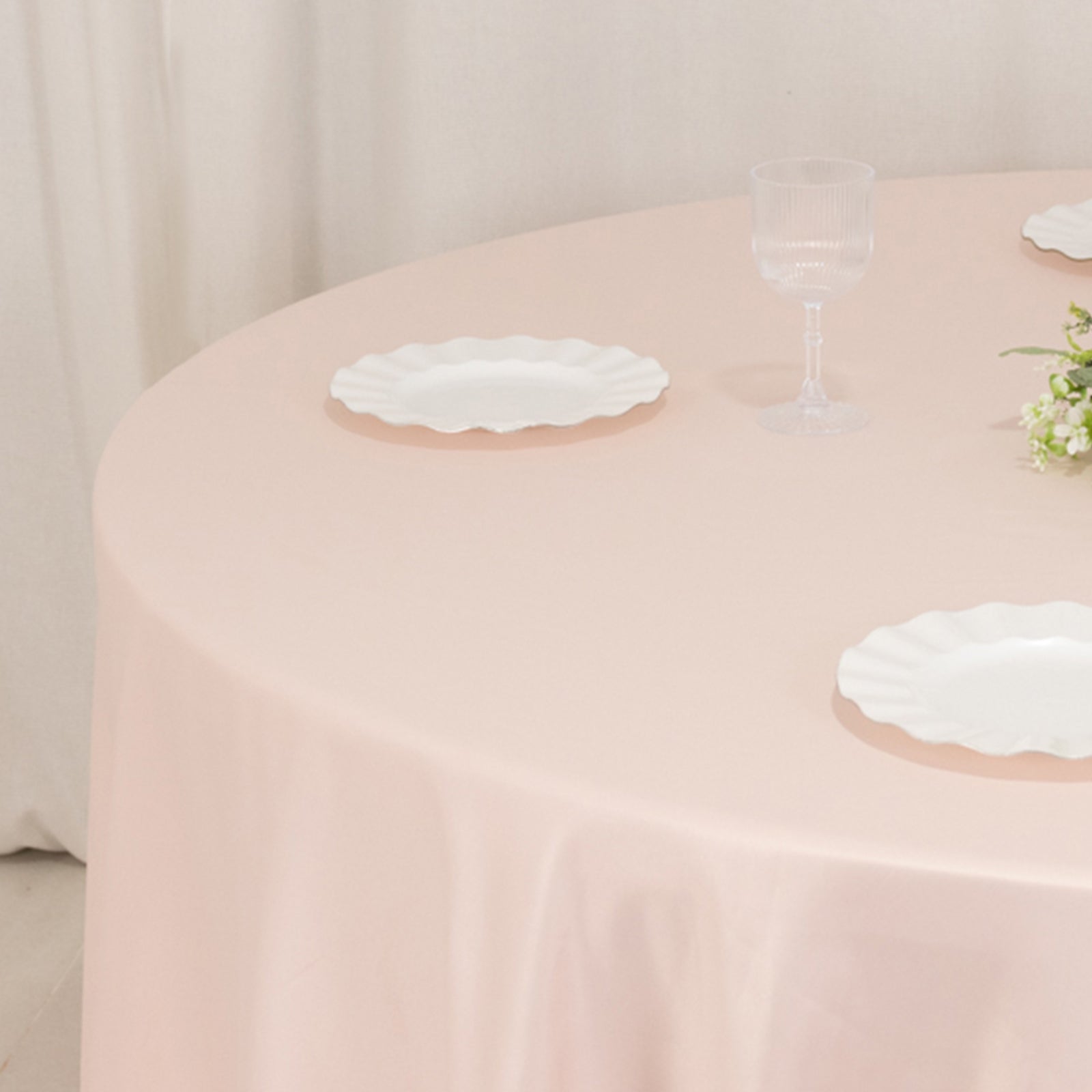 Blush satin round tablecloth on a dining table setting.