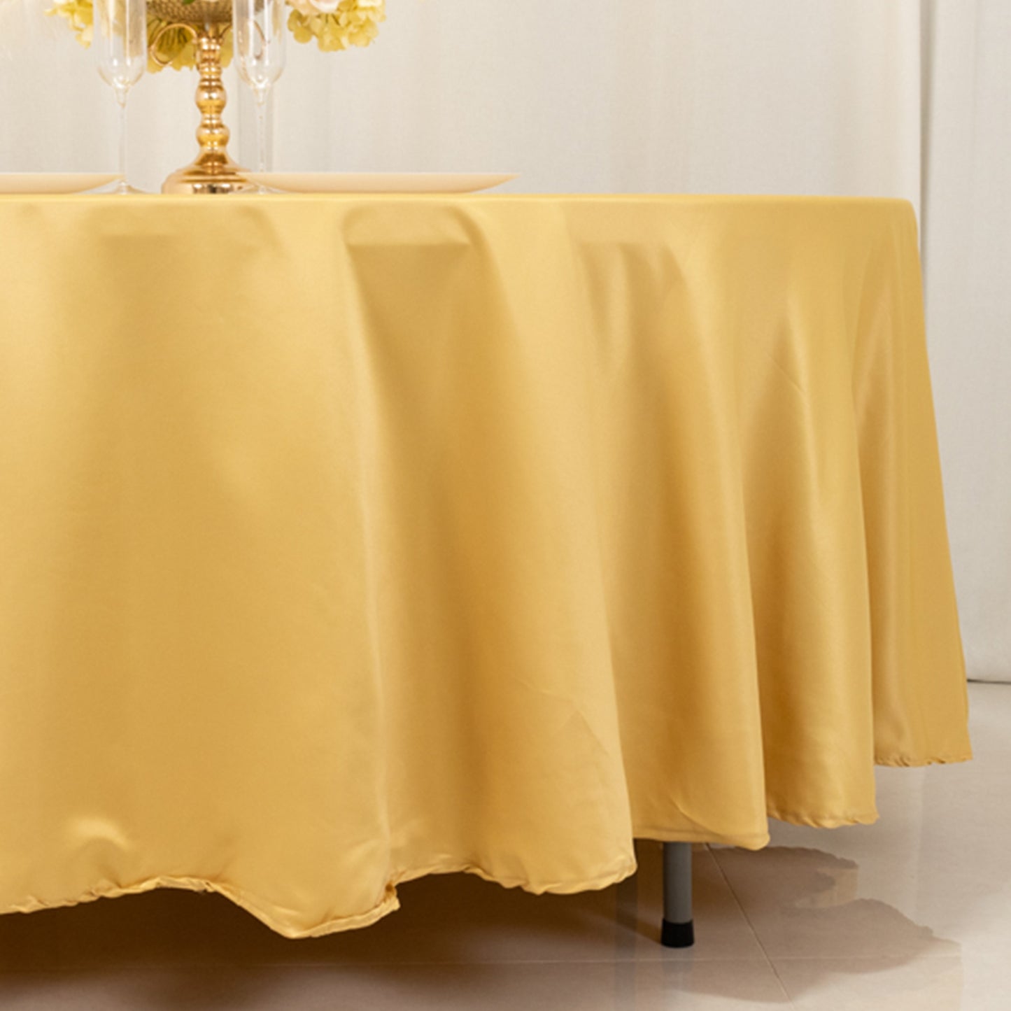 Champagne satin round tablecloth draping elegantly over a table.