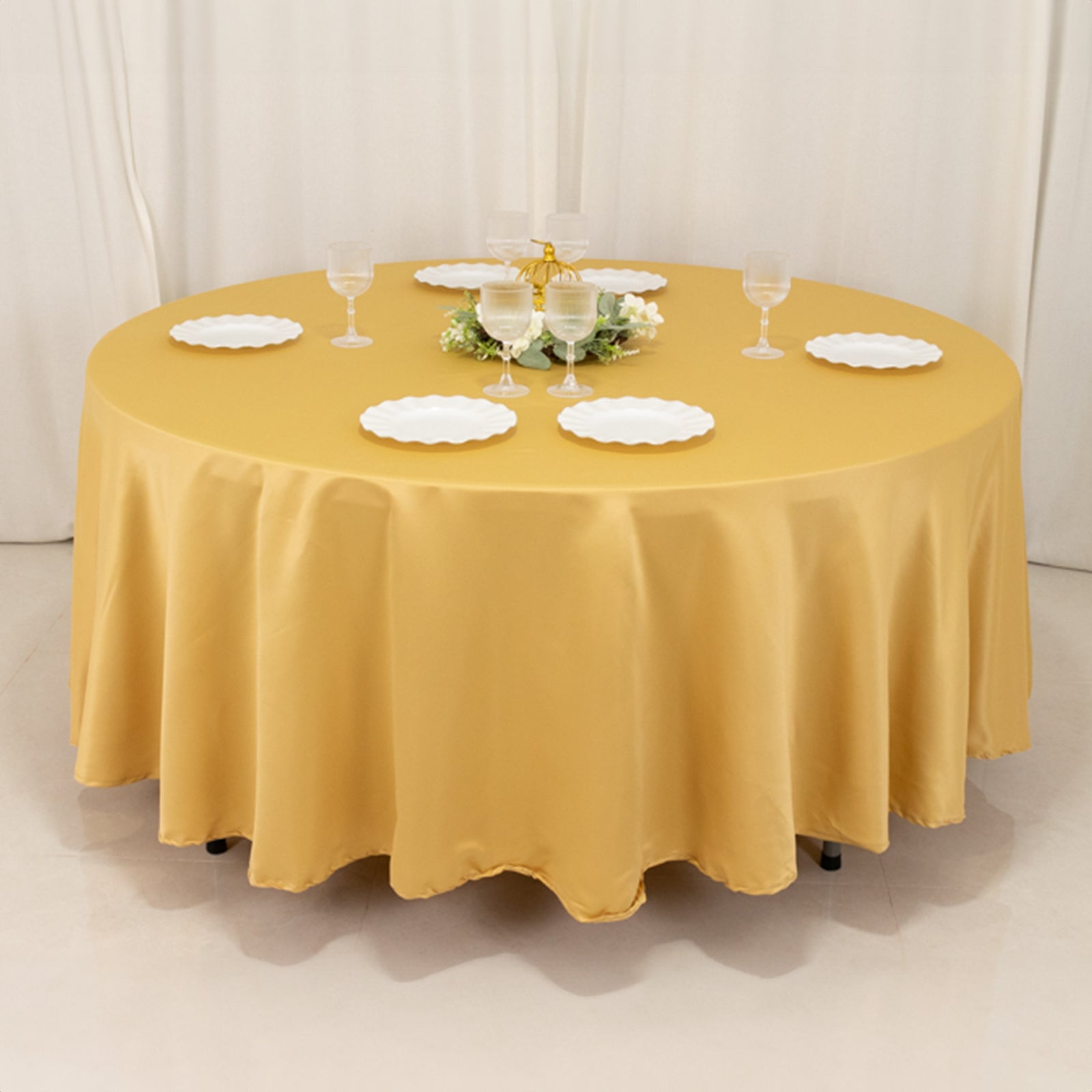 Champagne satin round tablecloth on a dining table with dishes and glasses.