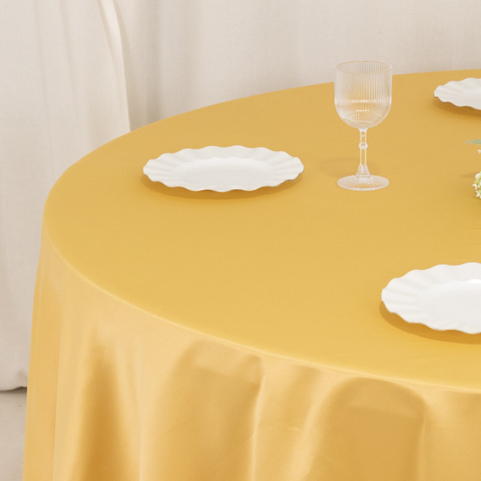 Champagne round satin tablecloth on a dining table.