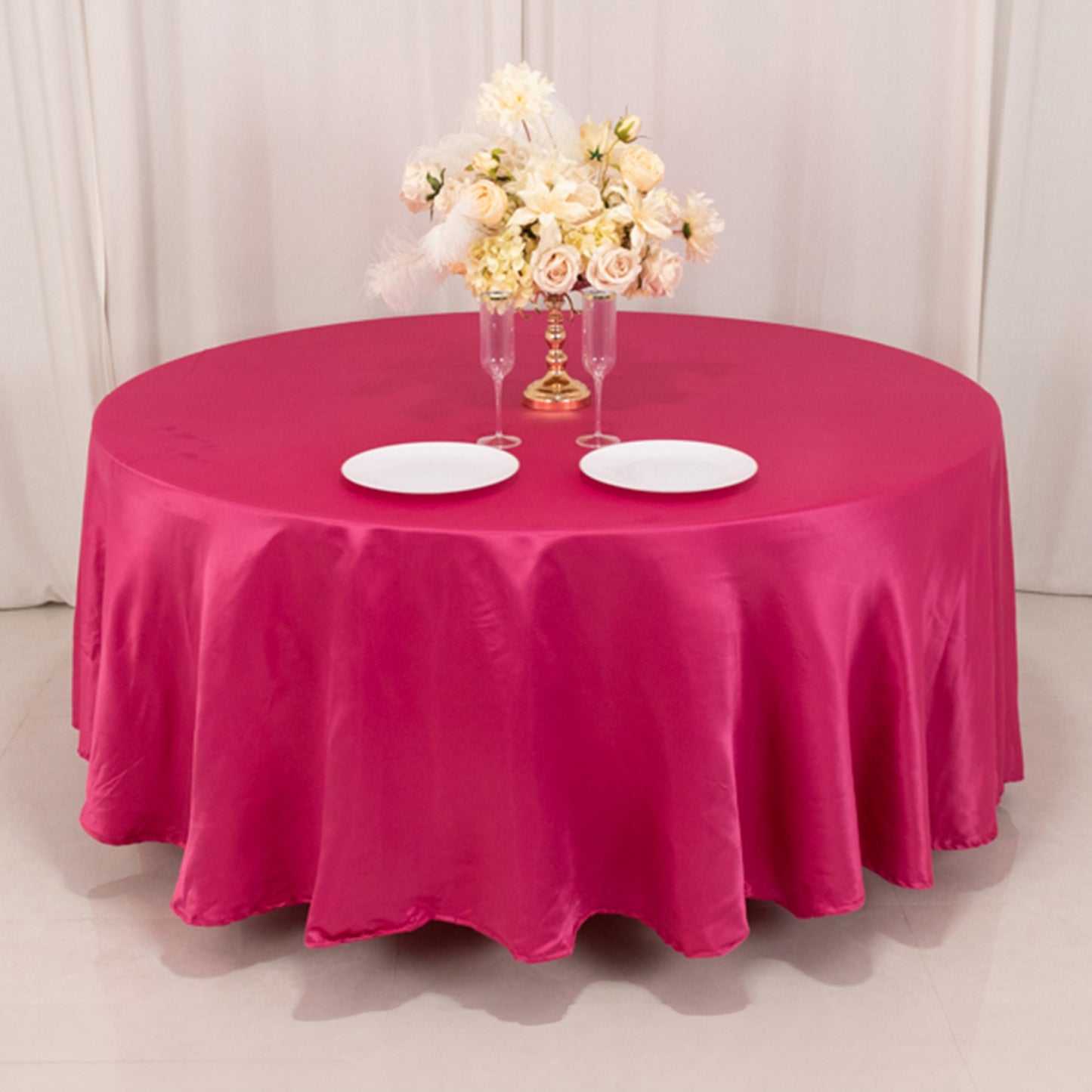 Fuchsia satin round tablecloth draped elegantly on a table with floral centerpiece.