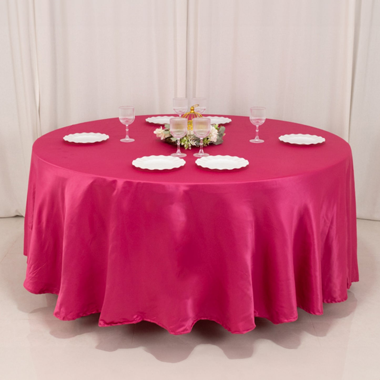 Fuchsia round satin tablecloth set for elegant dining occasions.