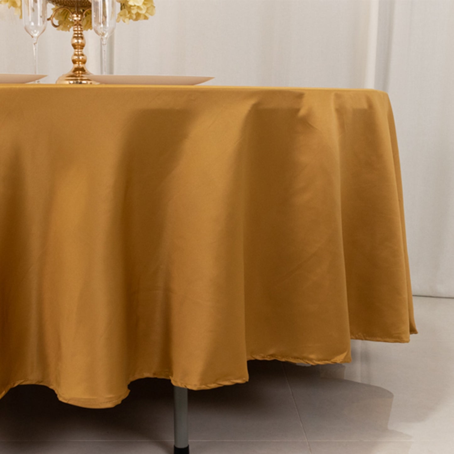 Gold satin round tablecloth for elegant dining settings.
