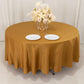Gold round tablecloth with elegant floral centerpiece and dinner plates.