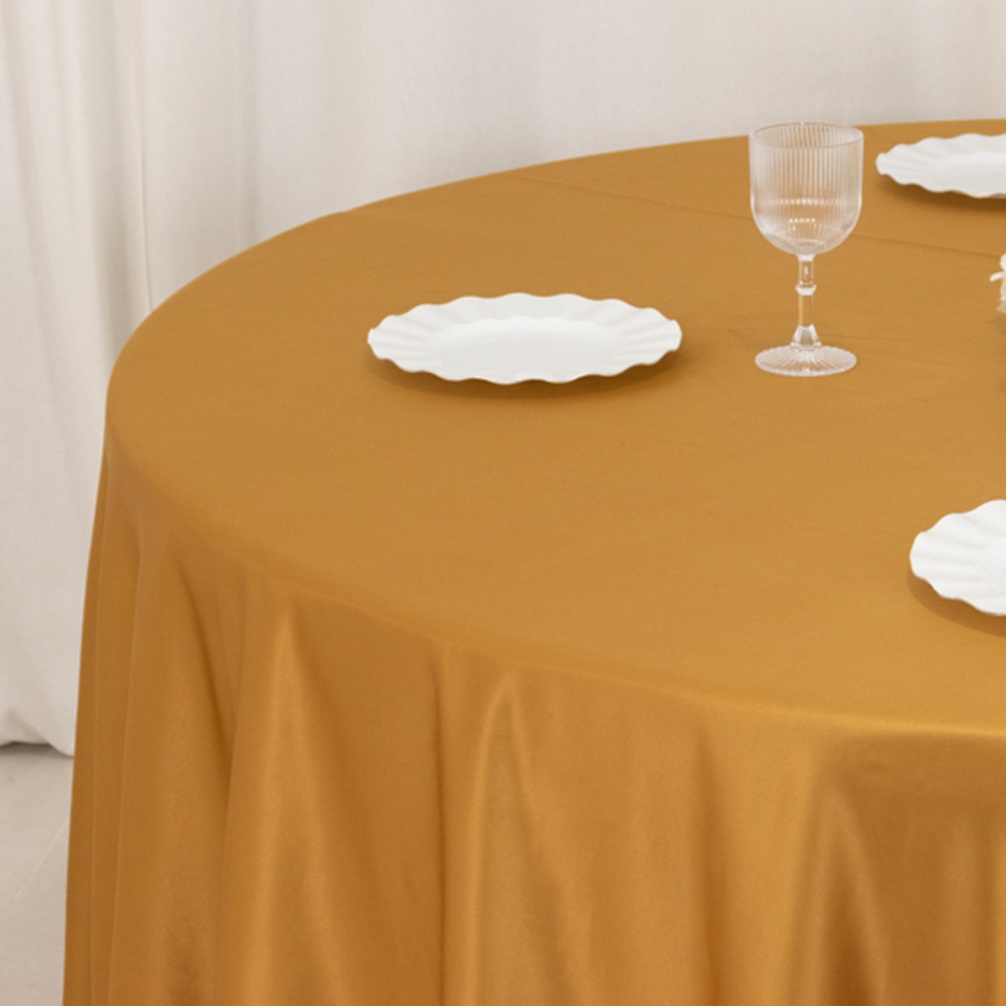 Gold satin round tablecloth on a dining table.