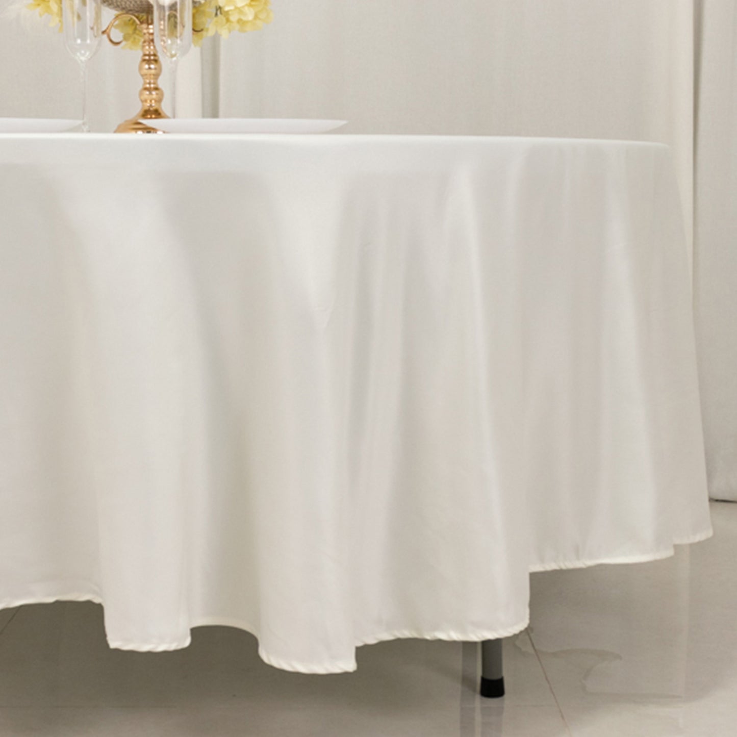 Ivory satin round tablecloth draping elegantly over a table.