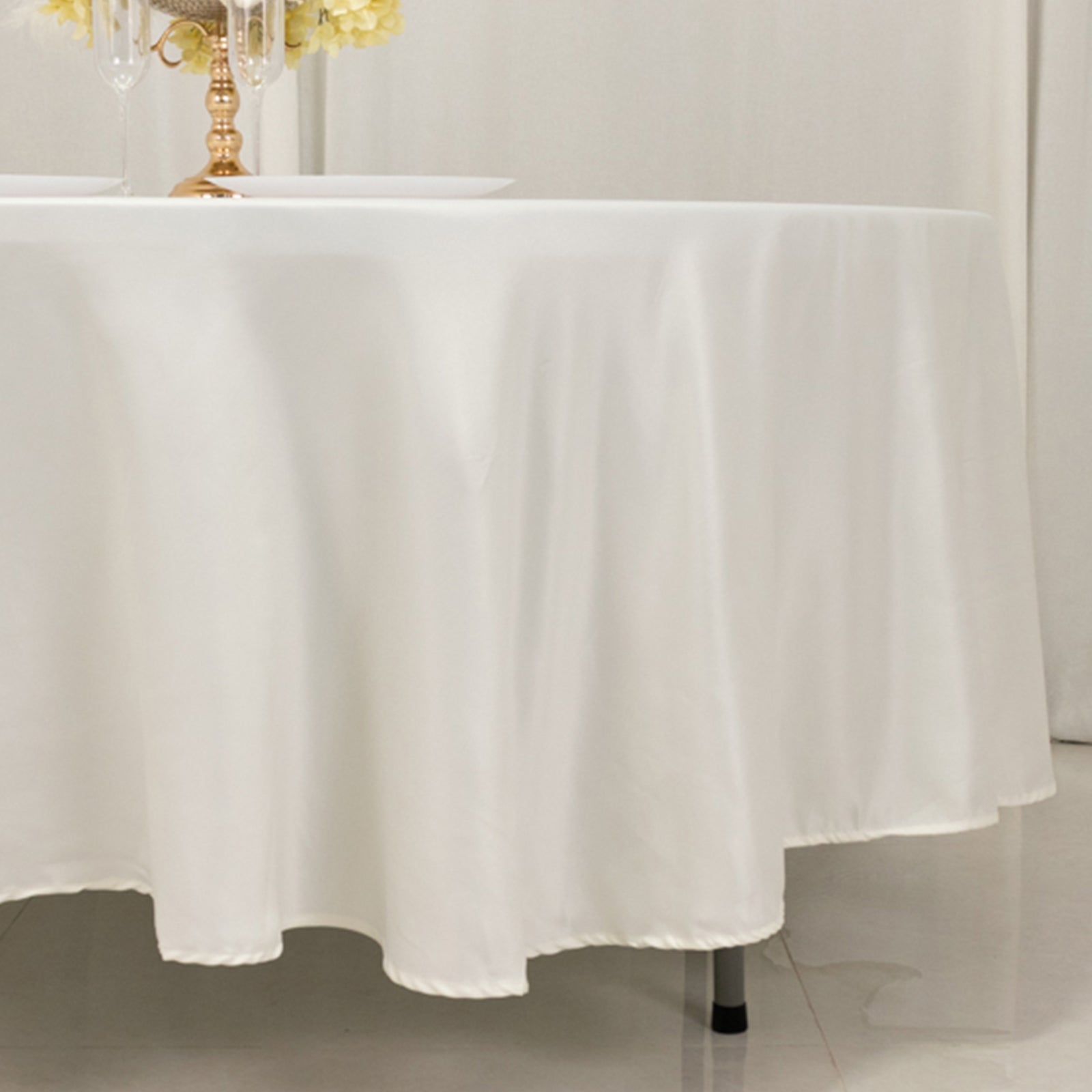 Ivory satin round tablecloth draping elegantly over a table.