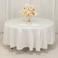 Ivory round satin tablecloth with a floral centerpiece and two plates.