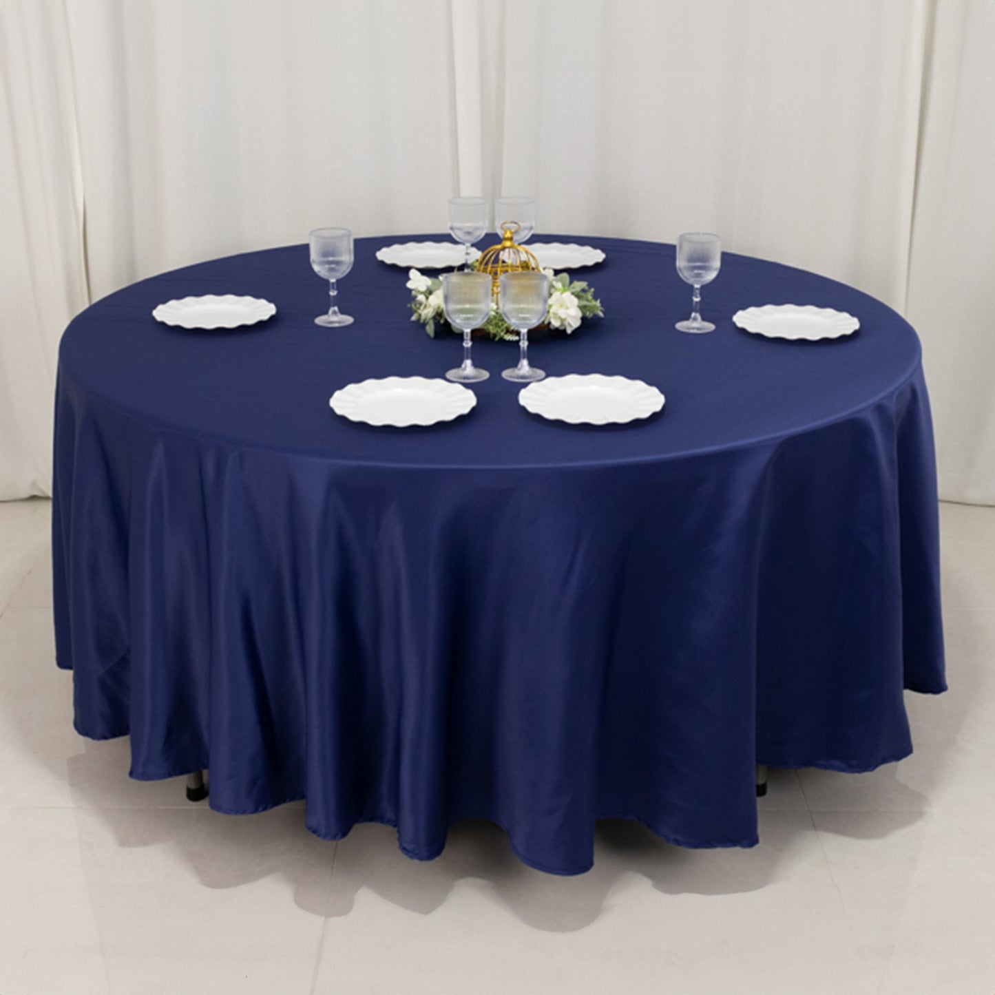 Navy blue round tablecloth on a dining table with plates and glasses.
