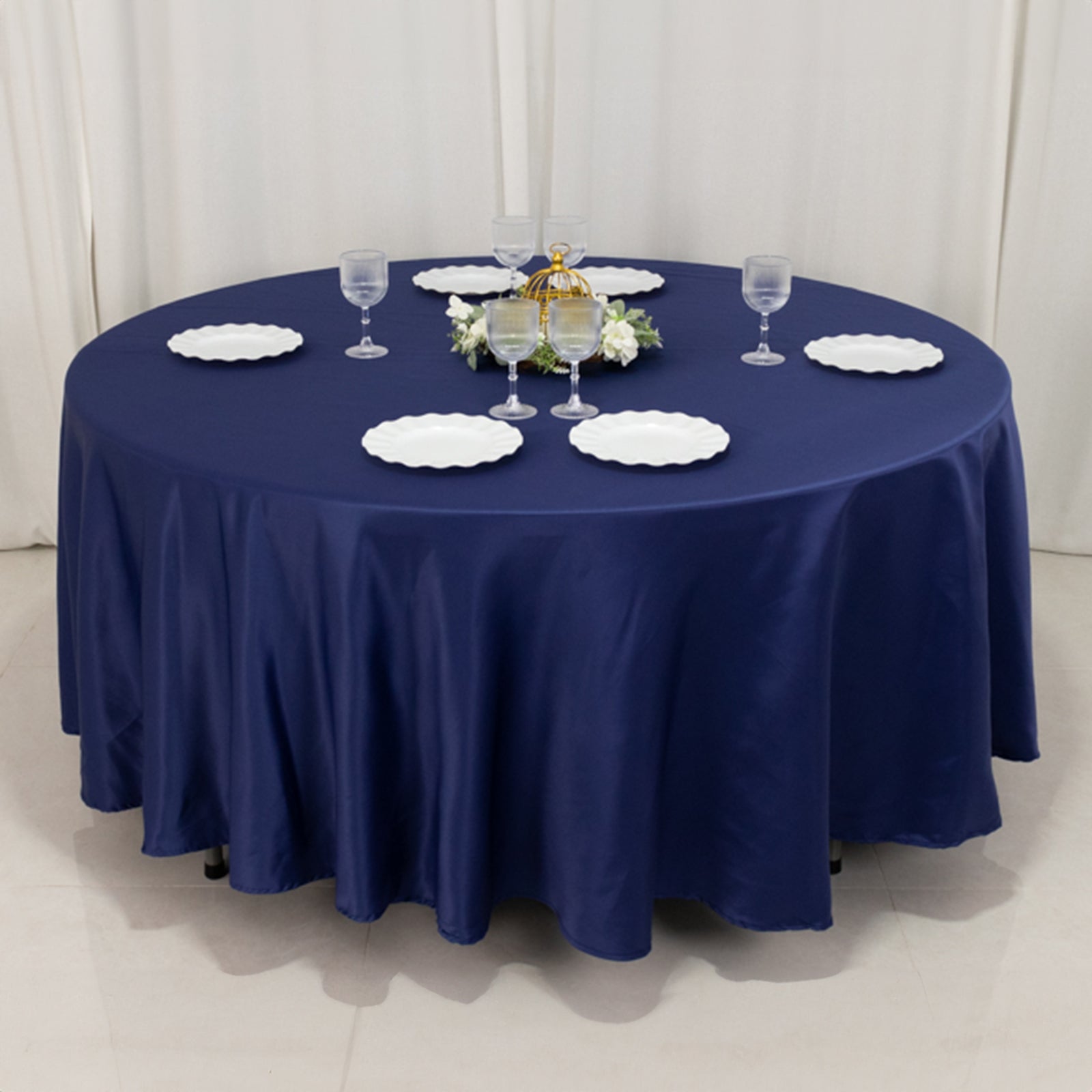 Navy blue round tablecloth on a dining table with plates and glasses.