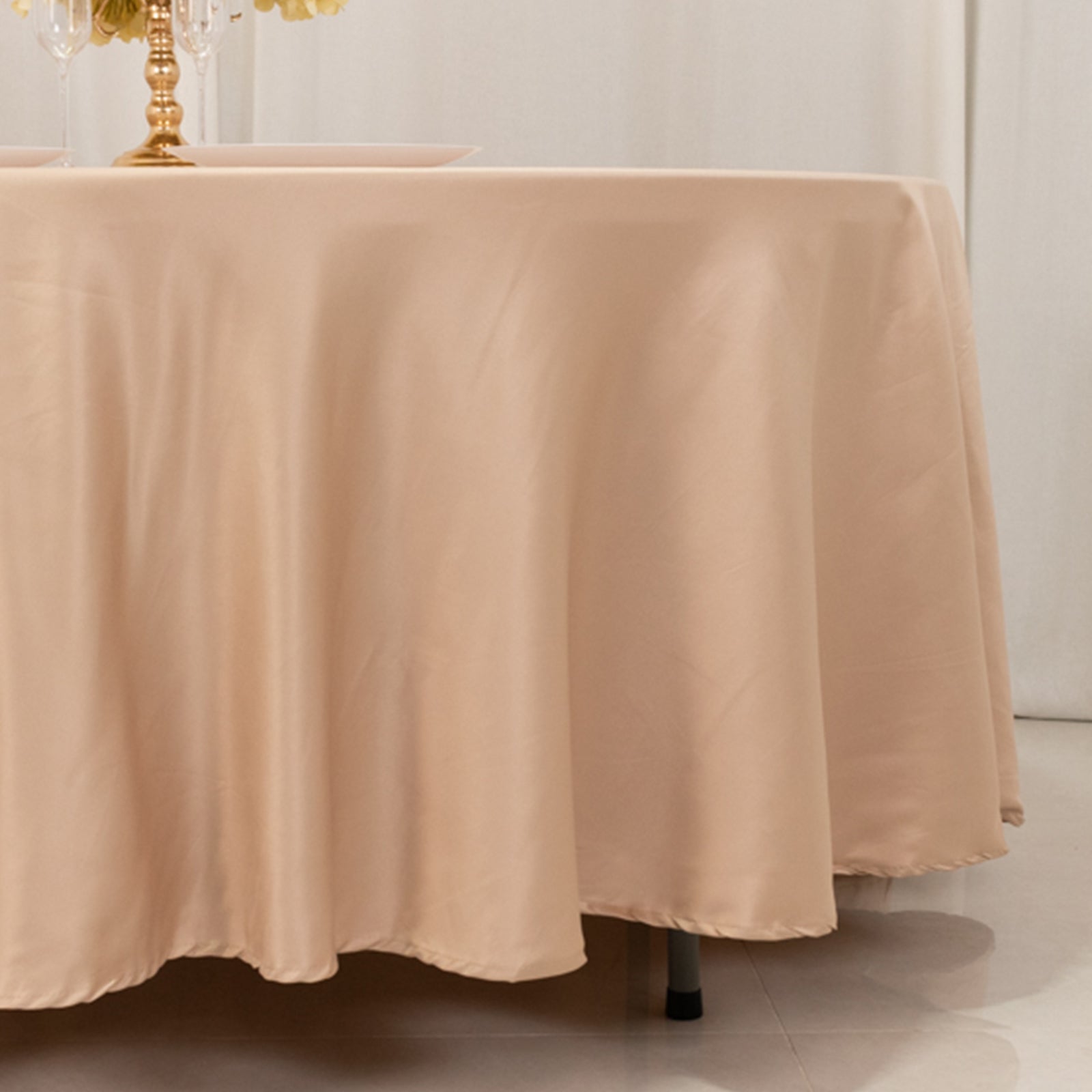 Nude satin round tablecloth on a dining table.