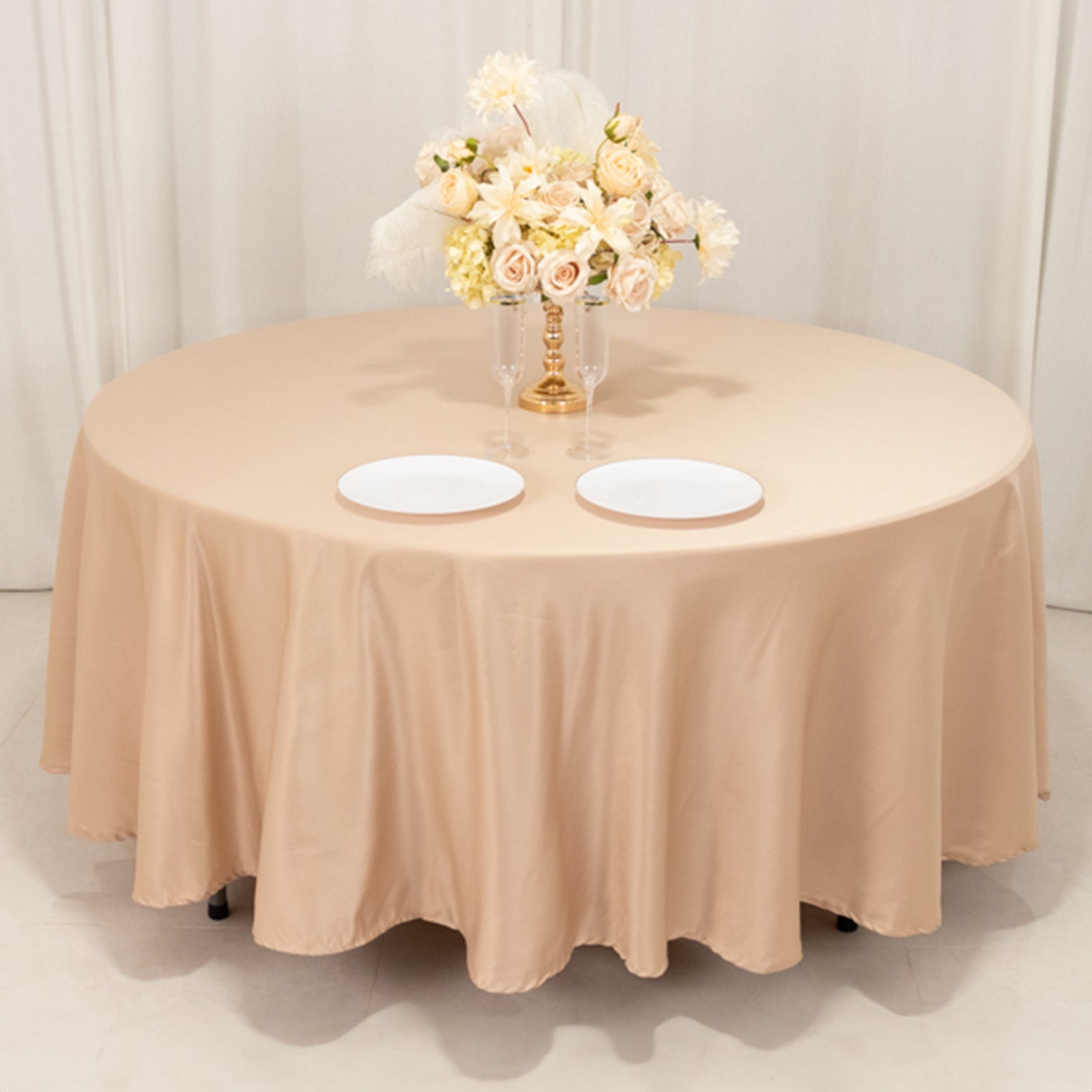 Nude satin round tablecloth on a dining table with floral centerpiece.