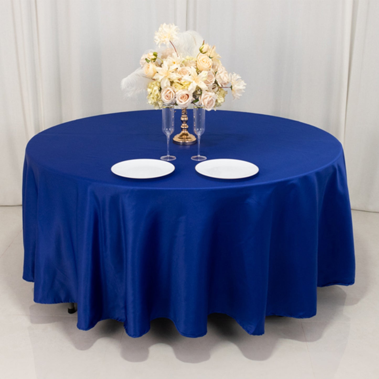 108" Royal Blue Lamour Satin Round Tablecloth on a table with floral arrangement.