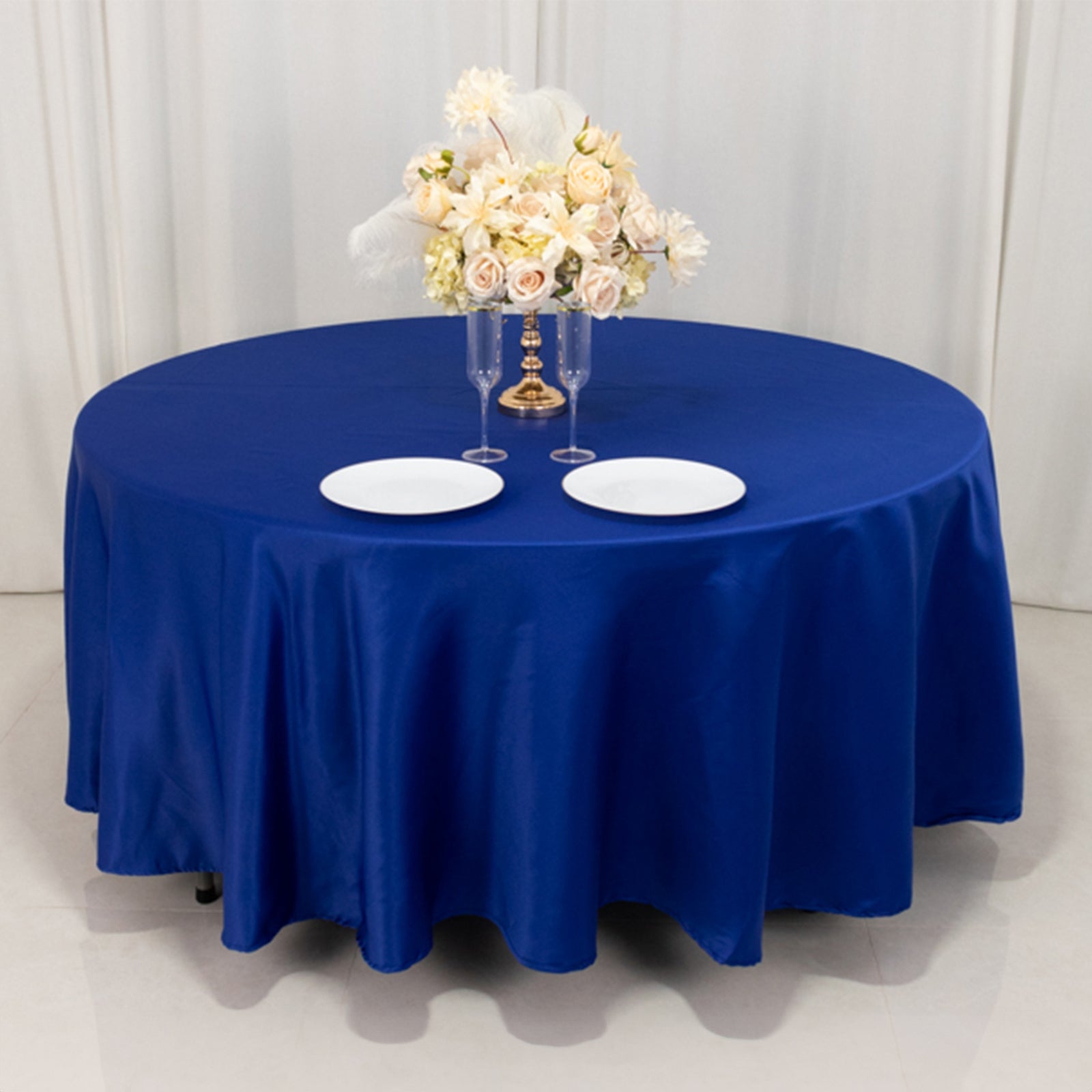 108" Royal Blue Lamour Satin Round Tablecloth on a table with floral arrangement.