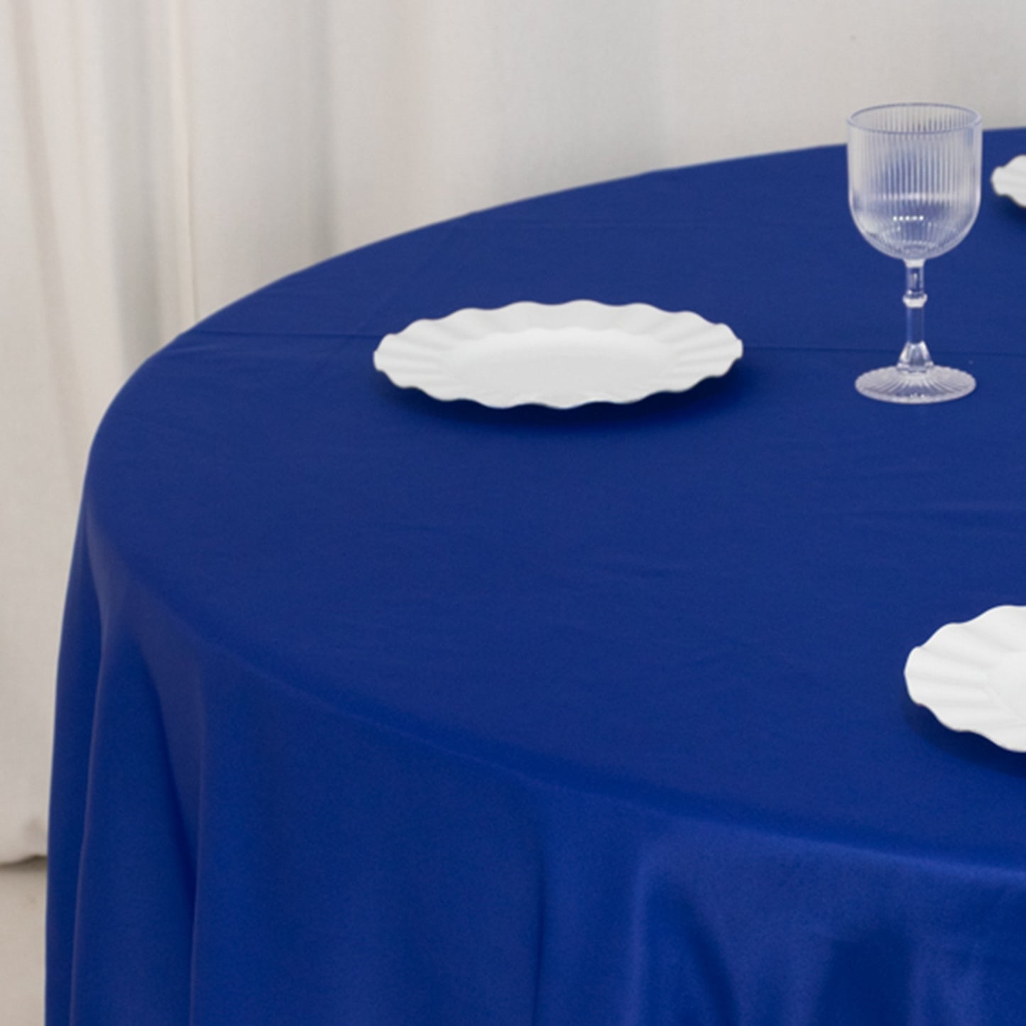 108" Royal Blue Lamour Satin Round Tablecloth on a table with white plates.