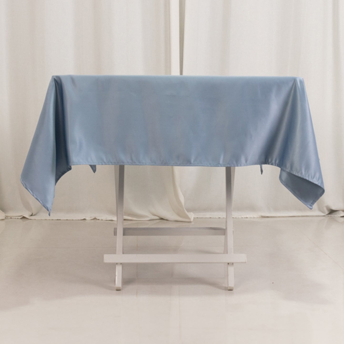 Dusty blue satin square tablecloth on a table.