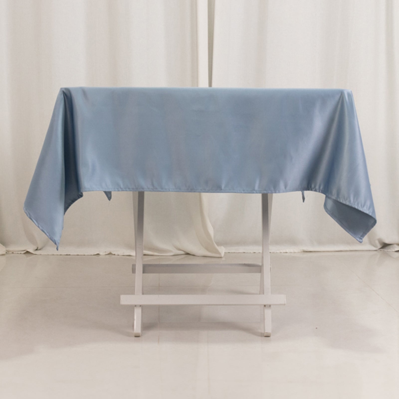 Dusty blue satin square tablecloth on a table.