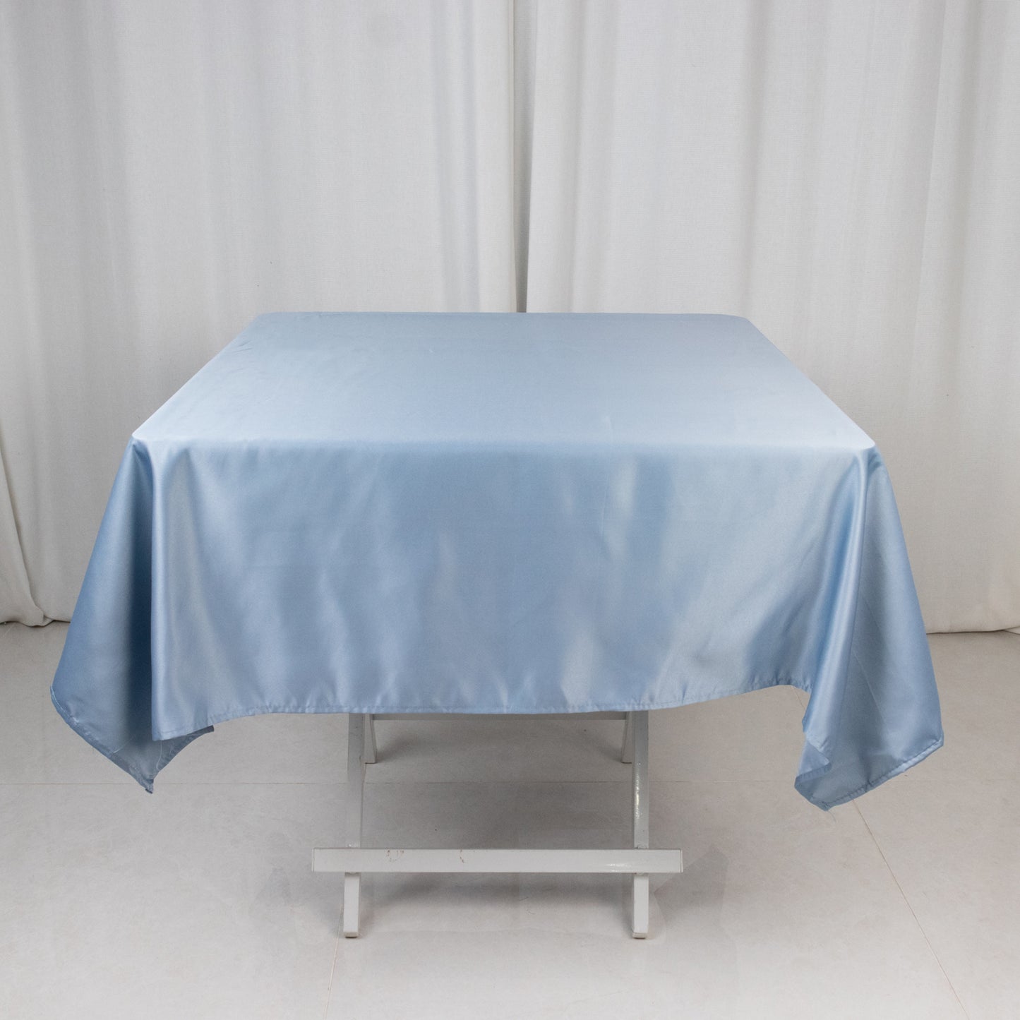 Dusty blue satin square tablecloth on a white table.