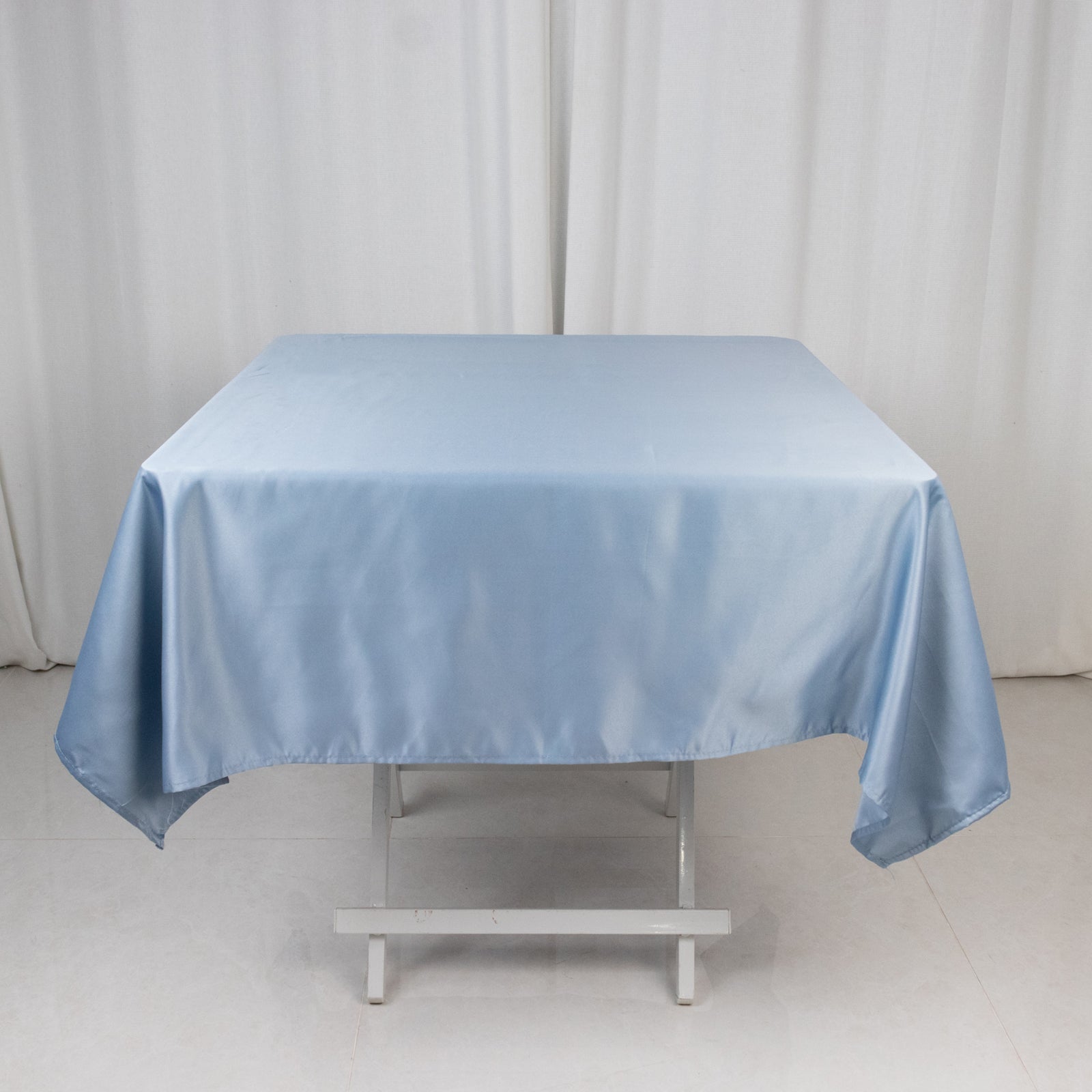 Dusty blue satin square tablecloth on a white table.