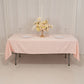 Blush satin tablecloth draped over a rectangle table with floral arrangement.