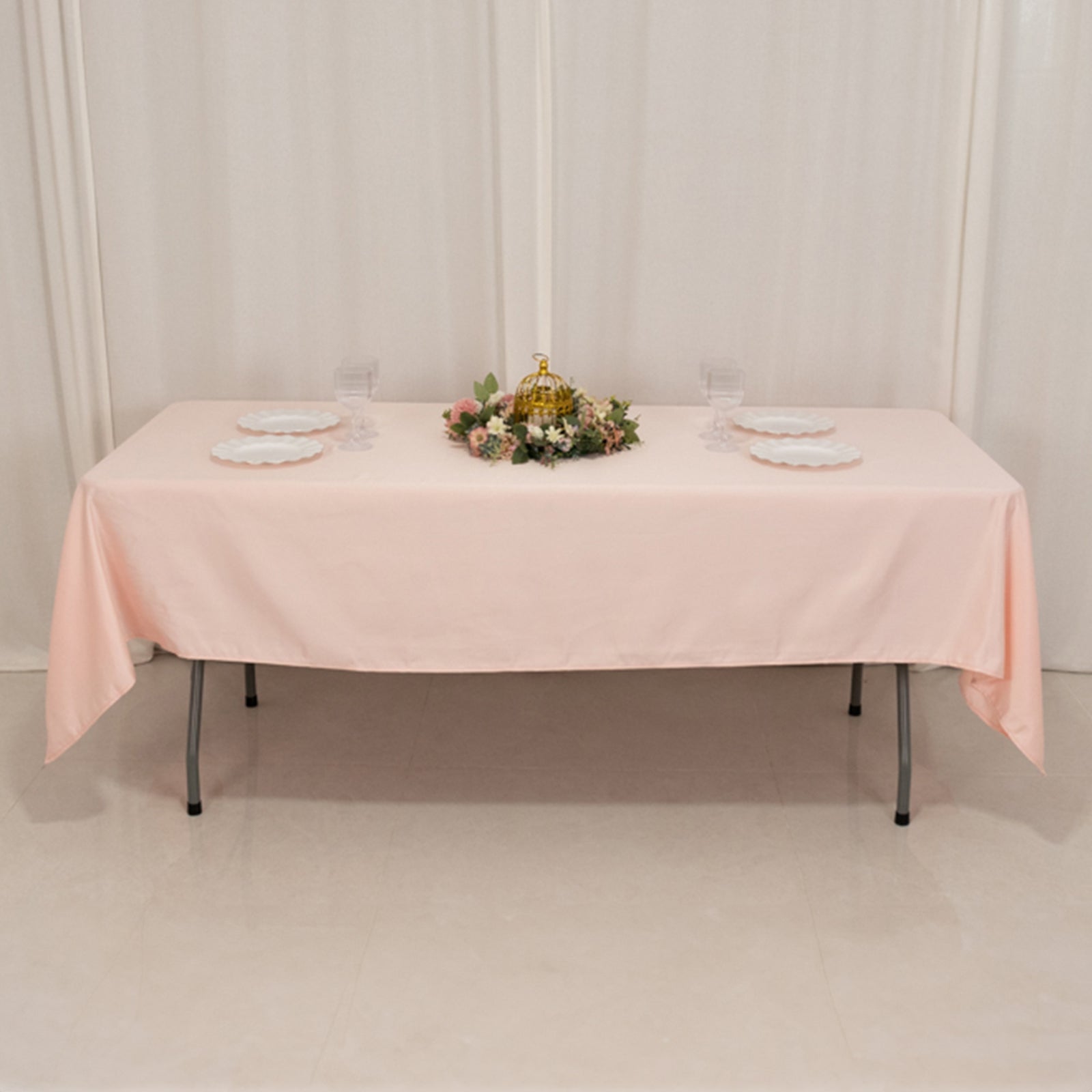 Blush satin rectangle tablecloth on a dining table with floral centerpiece.
