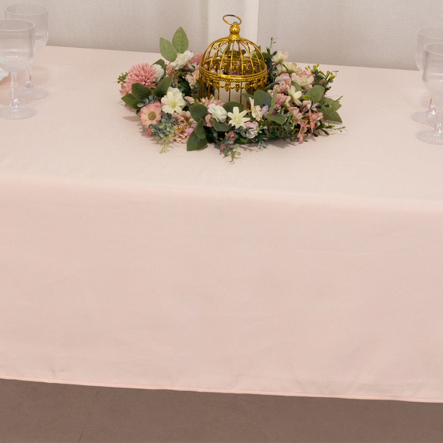 Blush satin rectangle tablecloth with floral centerpiece on a table.