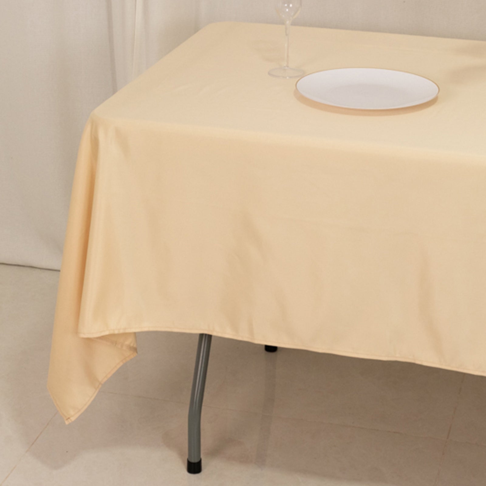 Beige satin rectangle tablecloth on a table with a plate.