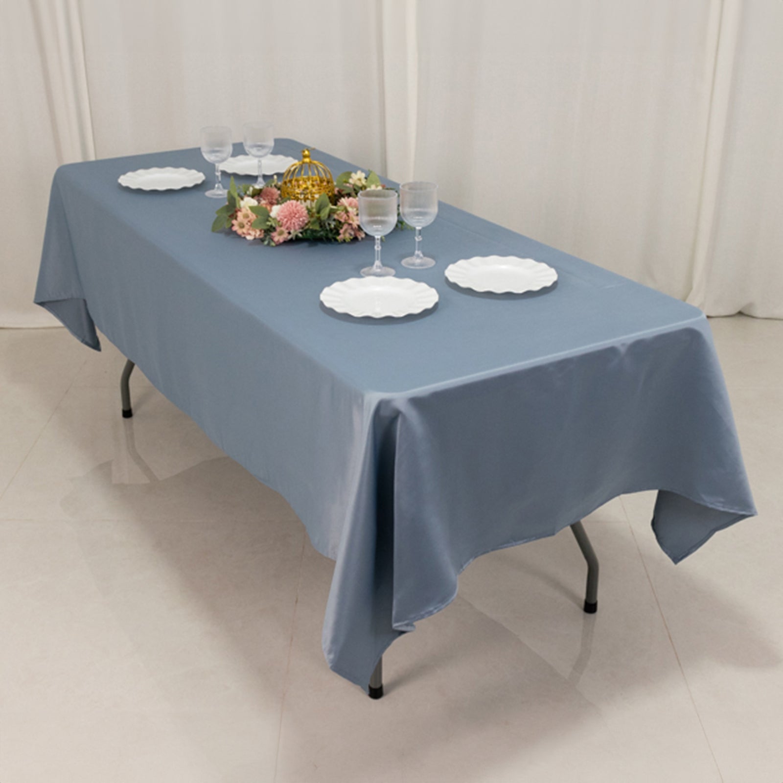 Dusty blue rectangle tablecloth on a dining table with decorative plates and flowers.