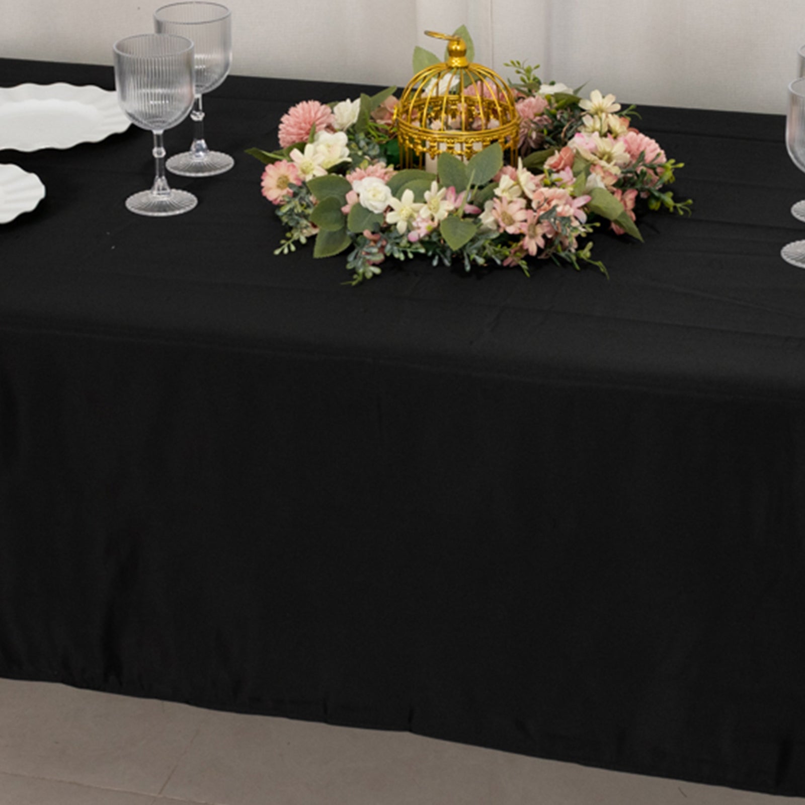 Black rectangular tablecloth on a dining table with floral decor.