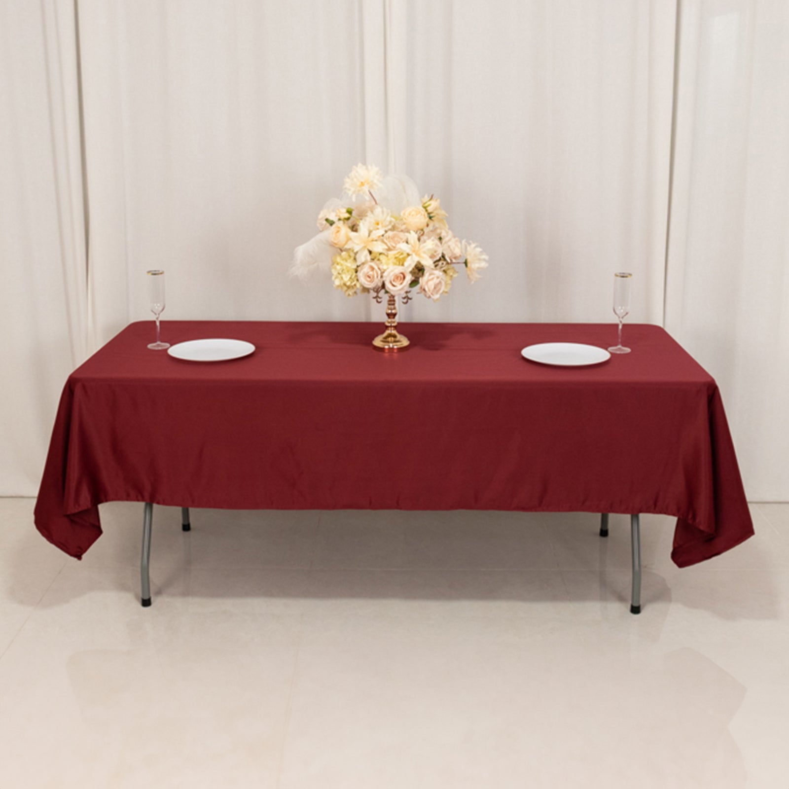 Burgundy satin rectangle tablecloth on a banquet table with a floral centerpiece.