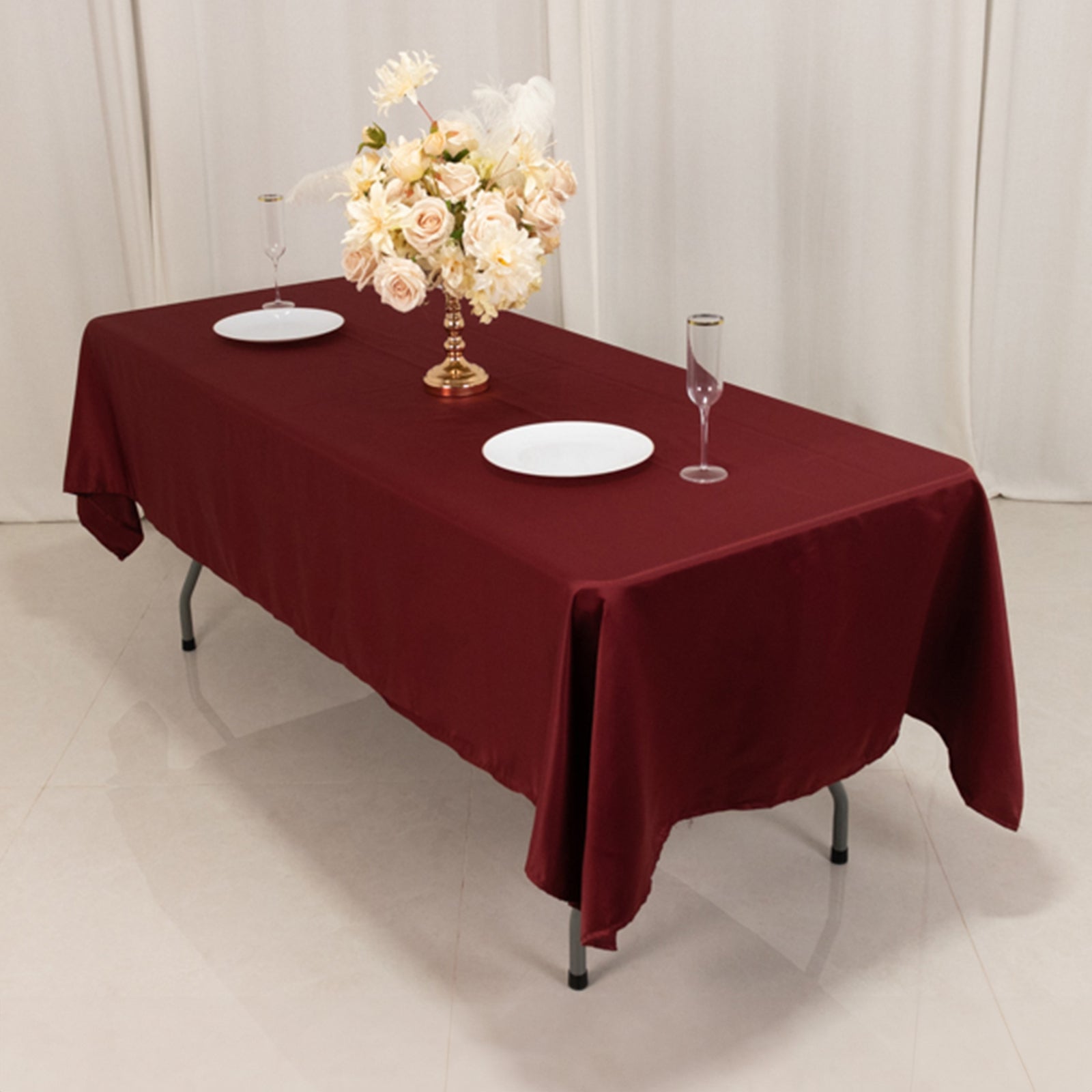 Burgundy satin rectangle tablecloth draped over a table with floral decor.