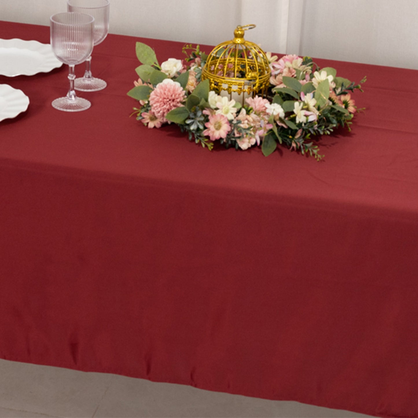 Burgundy satin rectangle tablecloth on a dining table with floral decor.