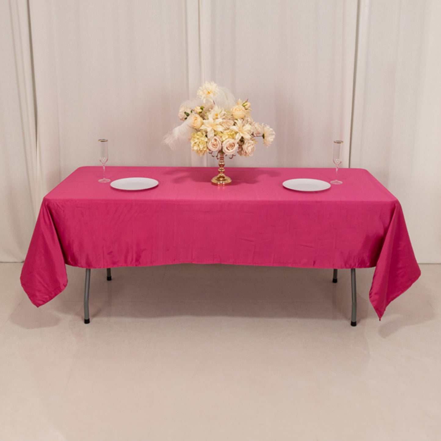Fuchsia satin rectangle tablecloth on a table set with floral centerpiece.