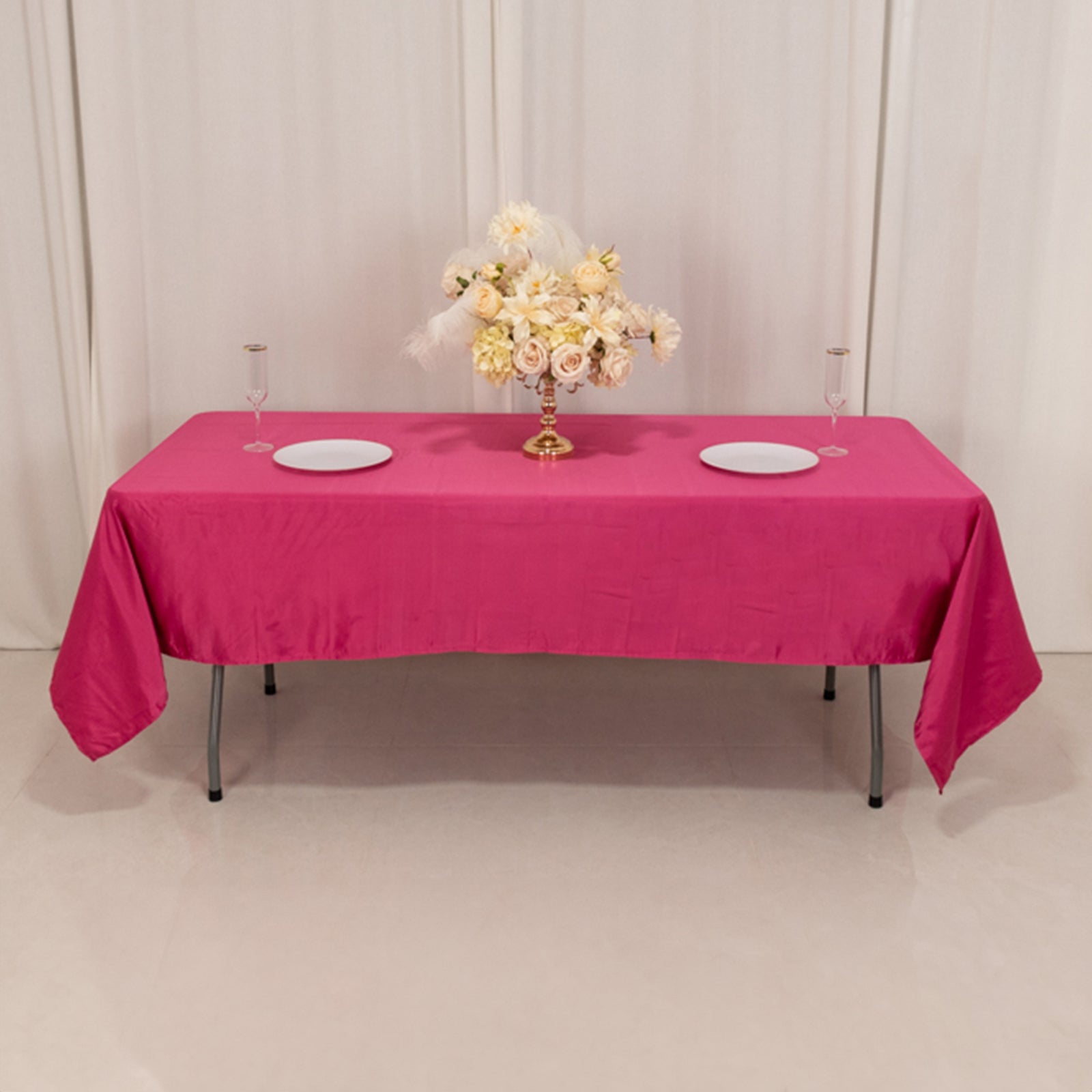 Fuchsia satin rectangle tablecloth on a table set with floral centerpiece.