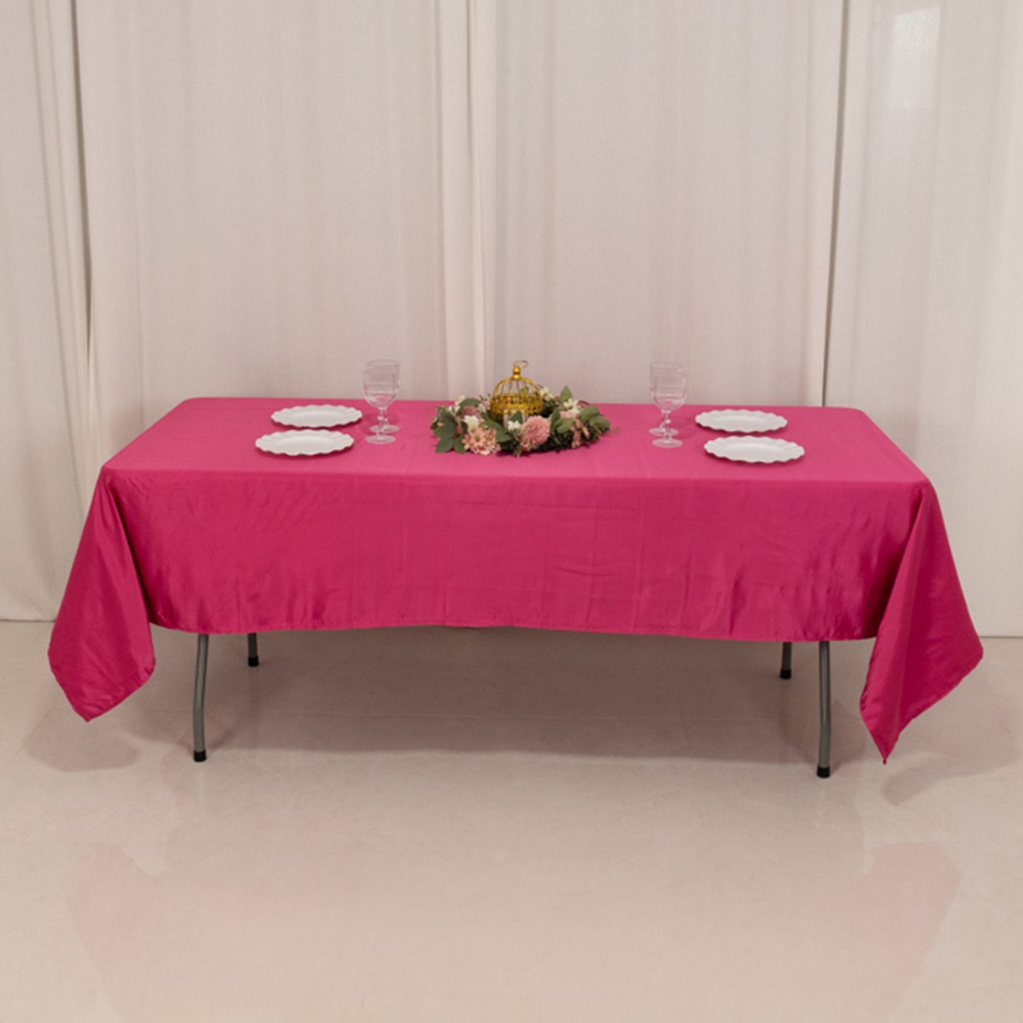 Fuchsia satin rectangle tablecloth on a dining table with floral centerpiece.
