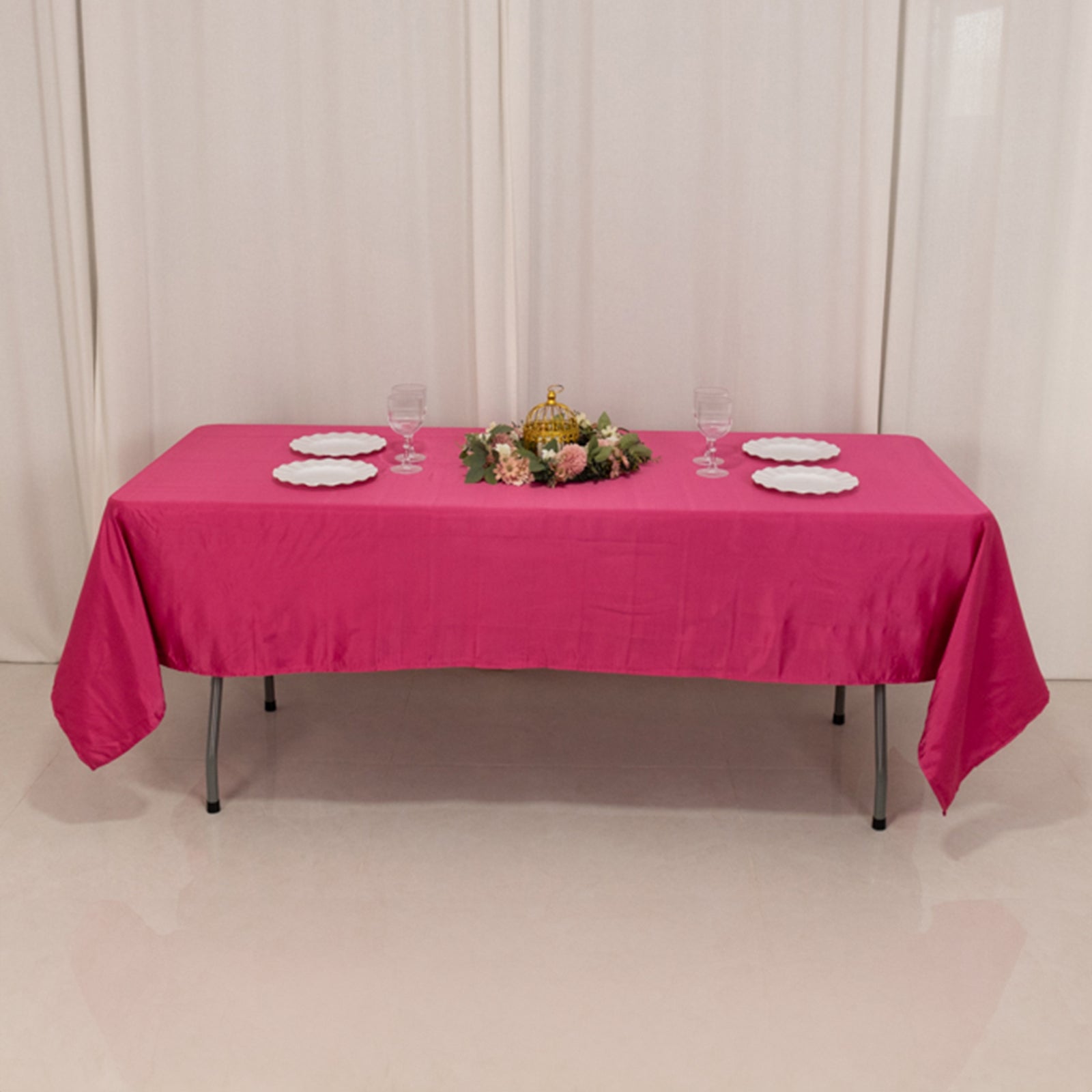 Fuchsia satin rectangle tablecloth on a dining table with floral centerpiece.