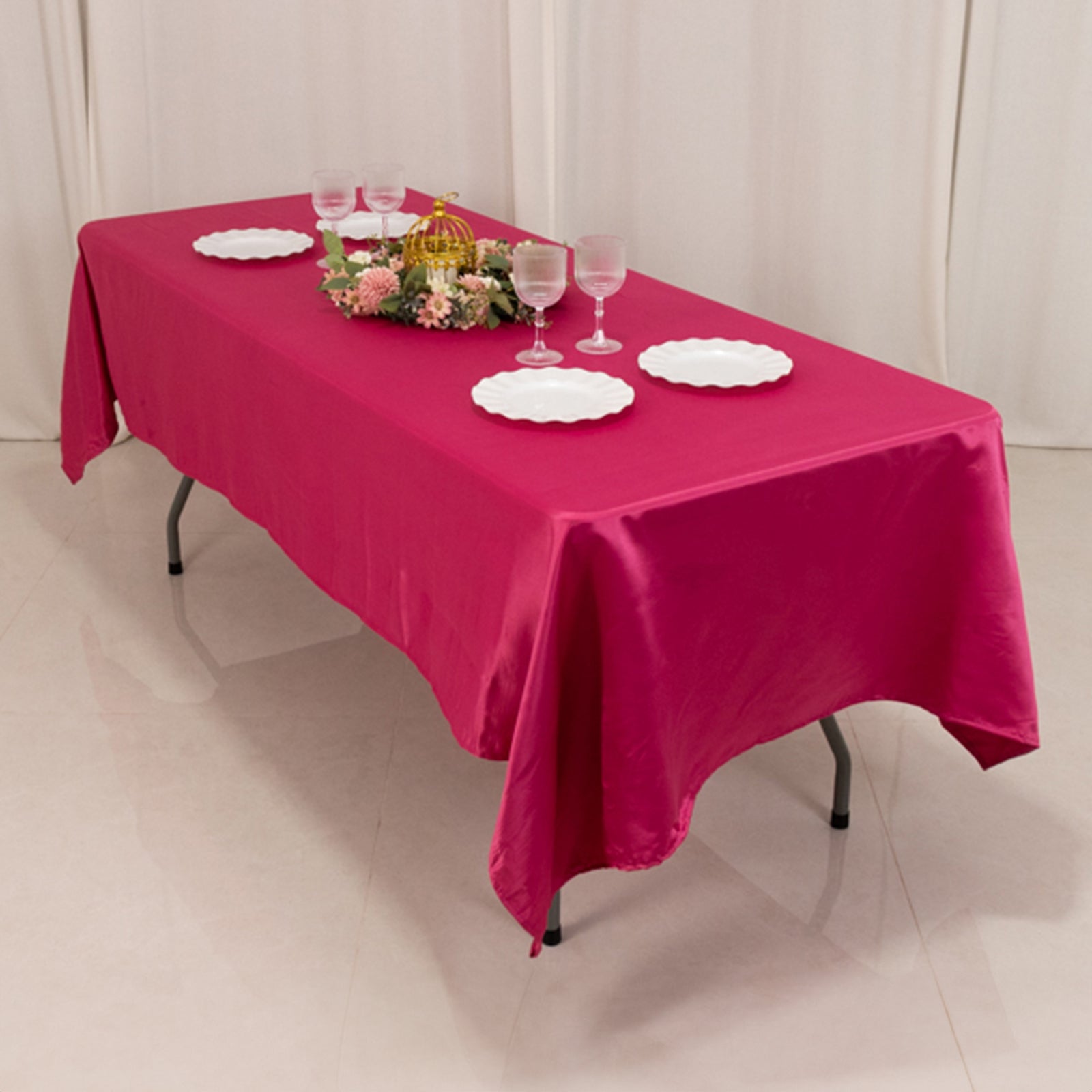 Fuchsia satin tablecloth on a dining table with plates and glasses.
