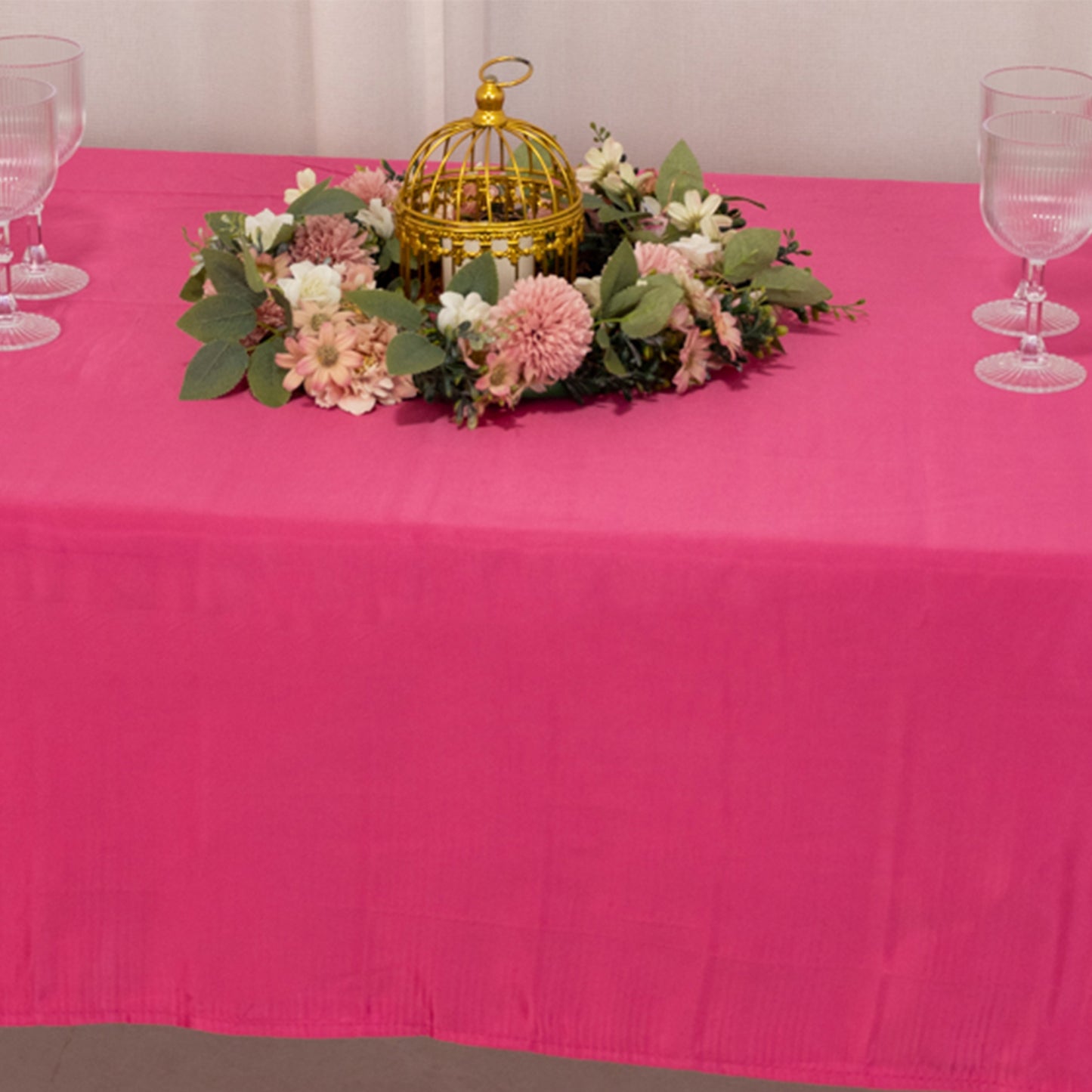 Fuchsia satin rectangle tablecloth on a dining table with floral centerpiece.