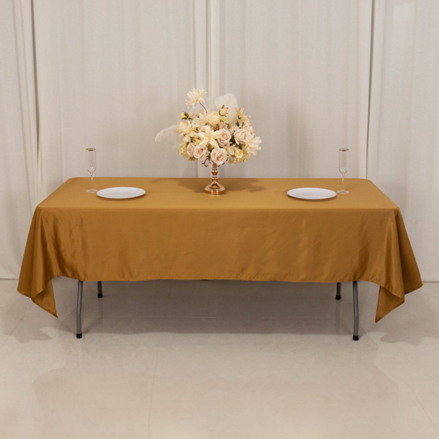 Gold satin rectangle tablecloth on a table with floral centerpiece.
