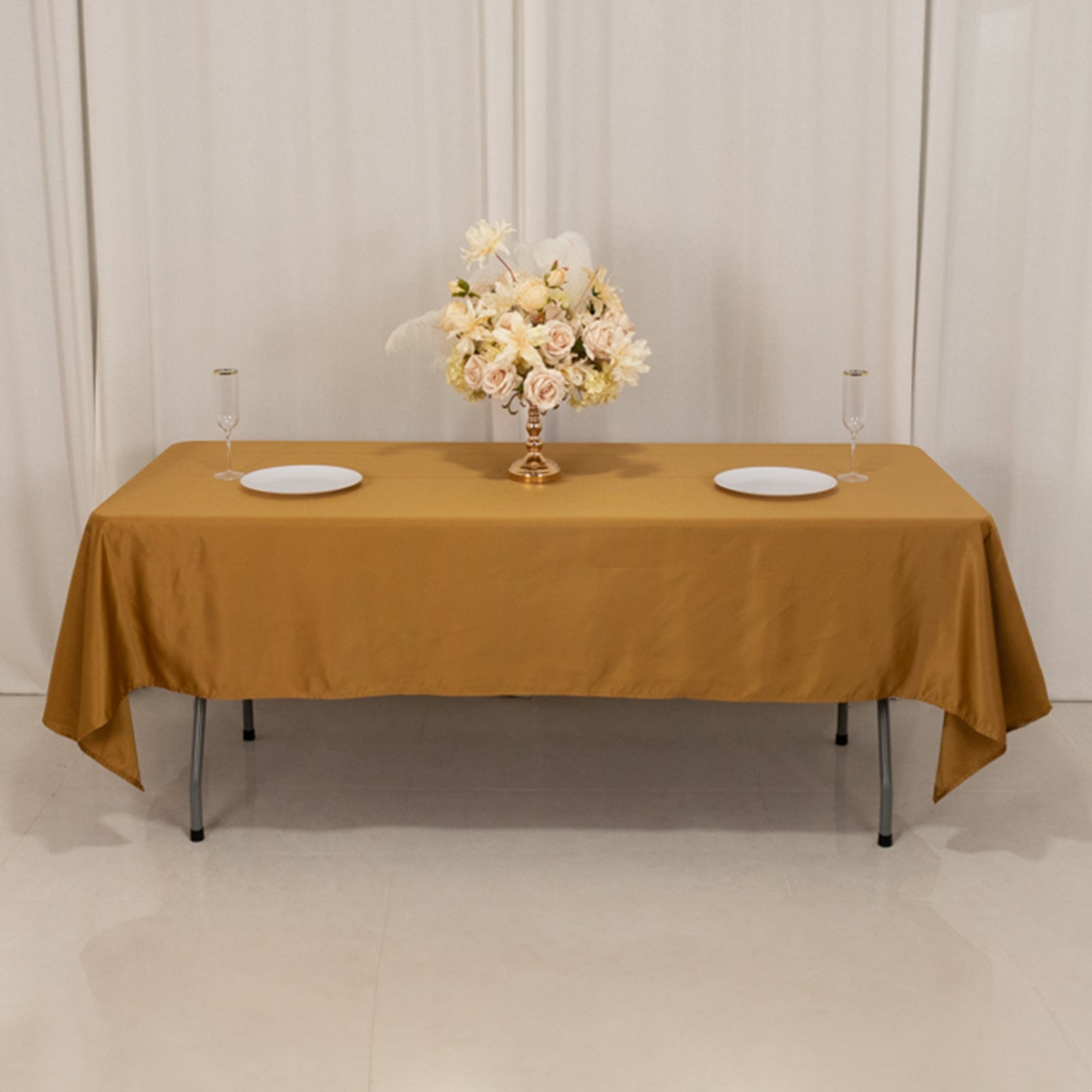 Gold satin rectangle tablecloth on a table with floral centerpiece.