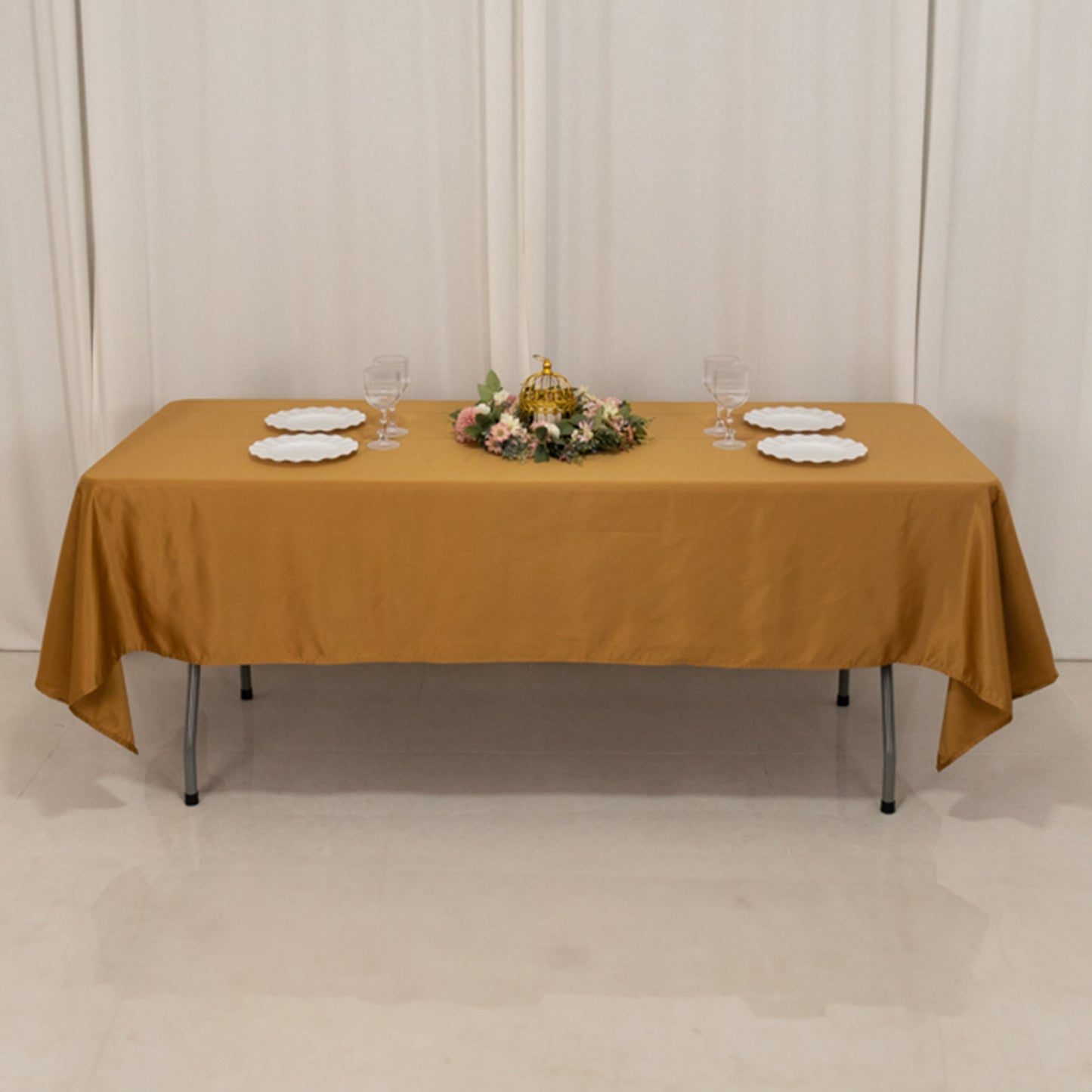 Gold satin rectangle tablecloth on a table with floral centerpiece.