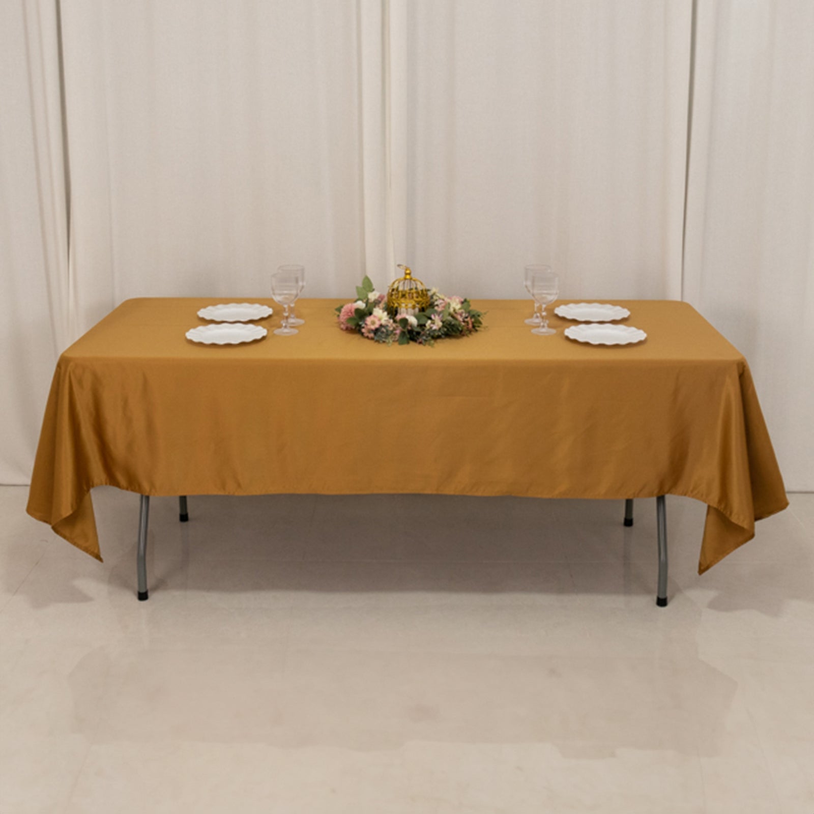 Gold satin rectangle tablecloth on a table with floral centerpiece.
