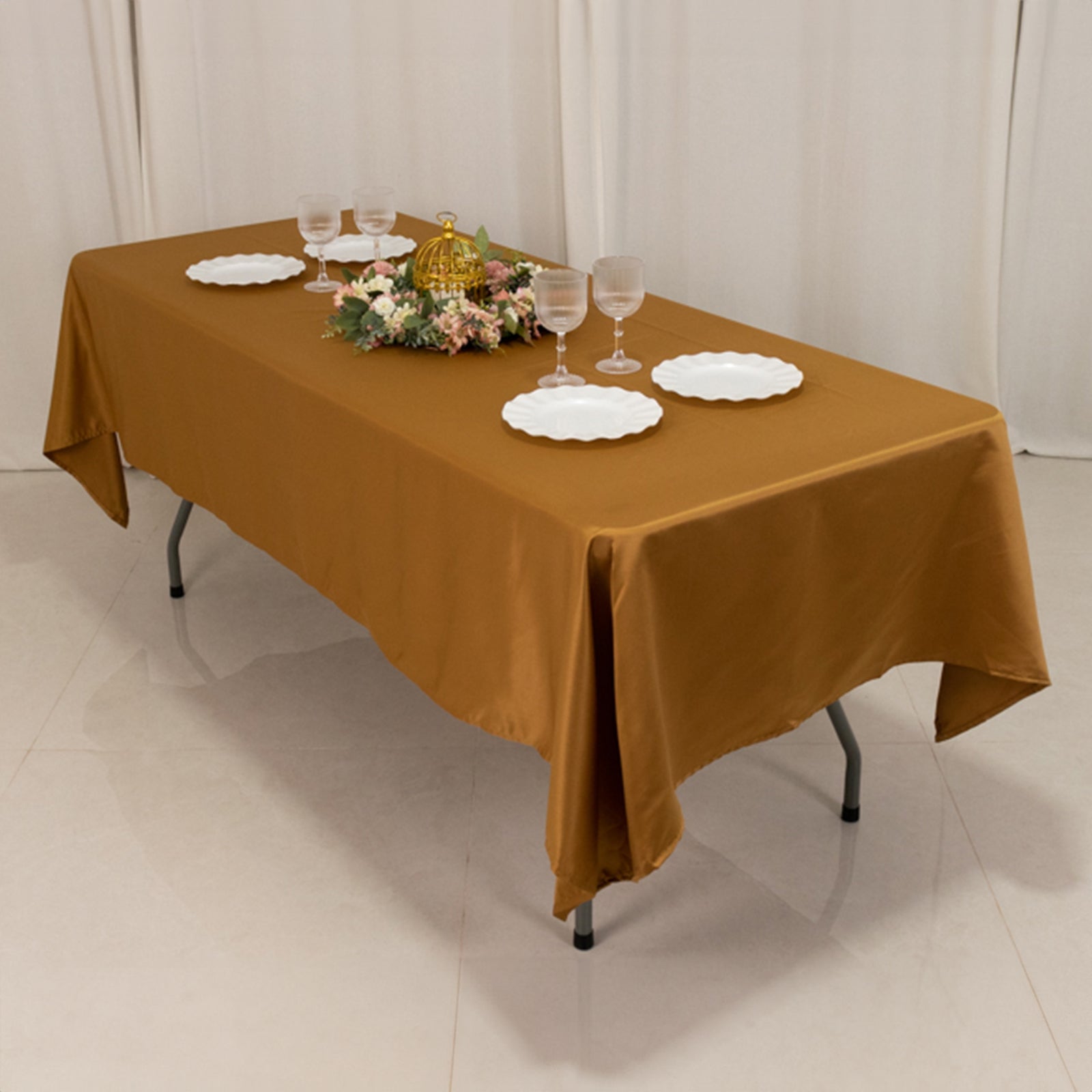 gold satin tablecloth on a rectangular table decorated with plates and flowers