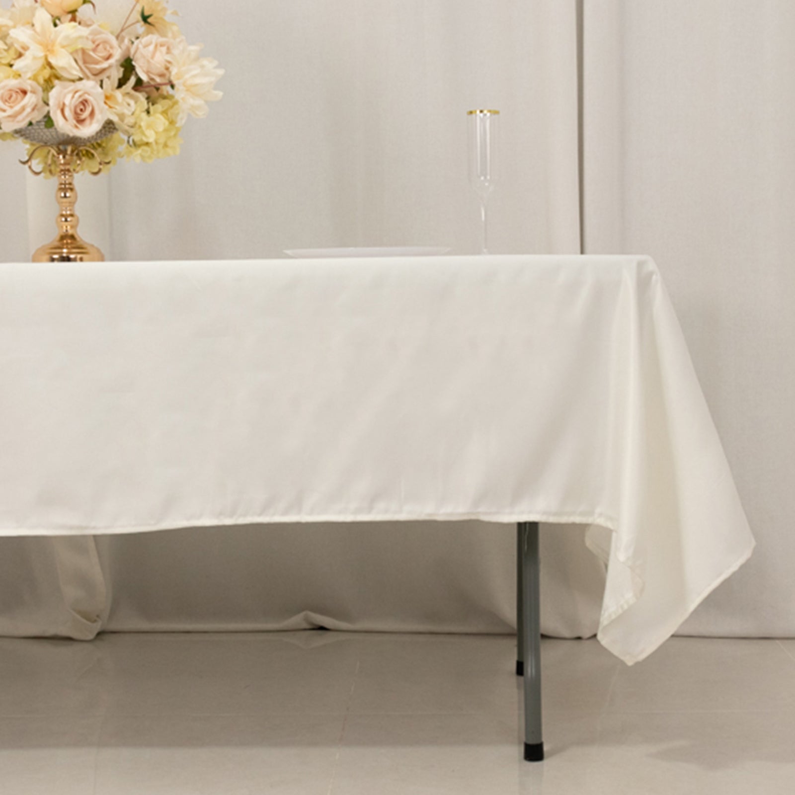 Ivory satin tablecloth 60"x102" on a table with floral arrangement.