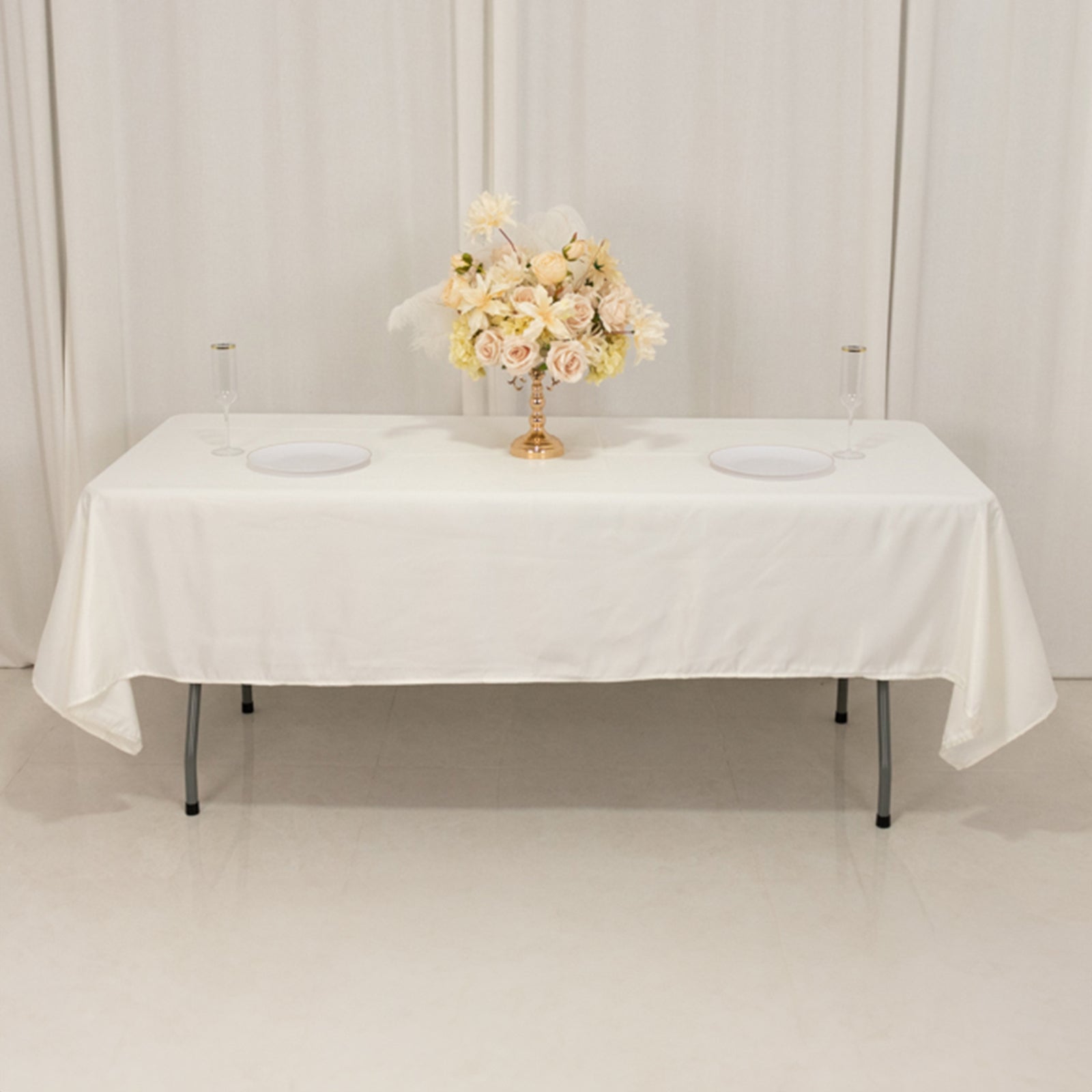 Ivory Lamour satin rectangle tablecloth on a table with floral centerpiece.