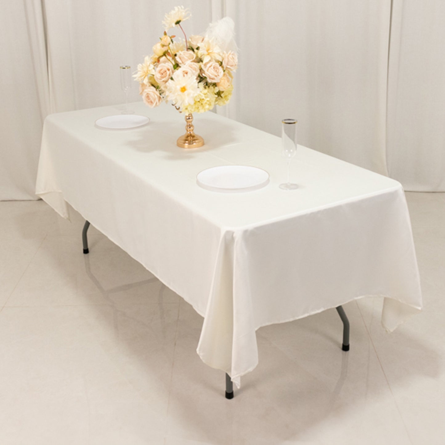 Ivory satin rectangle tablecloth on a banquet table with floral centerpiece.